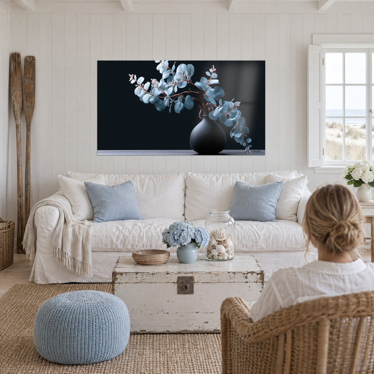 Wall art Eucalyptus leaves in blue-grey on a black background, matte black vase, hung above a sofa in a bright living room