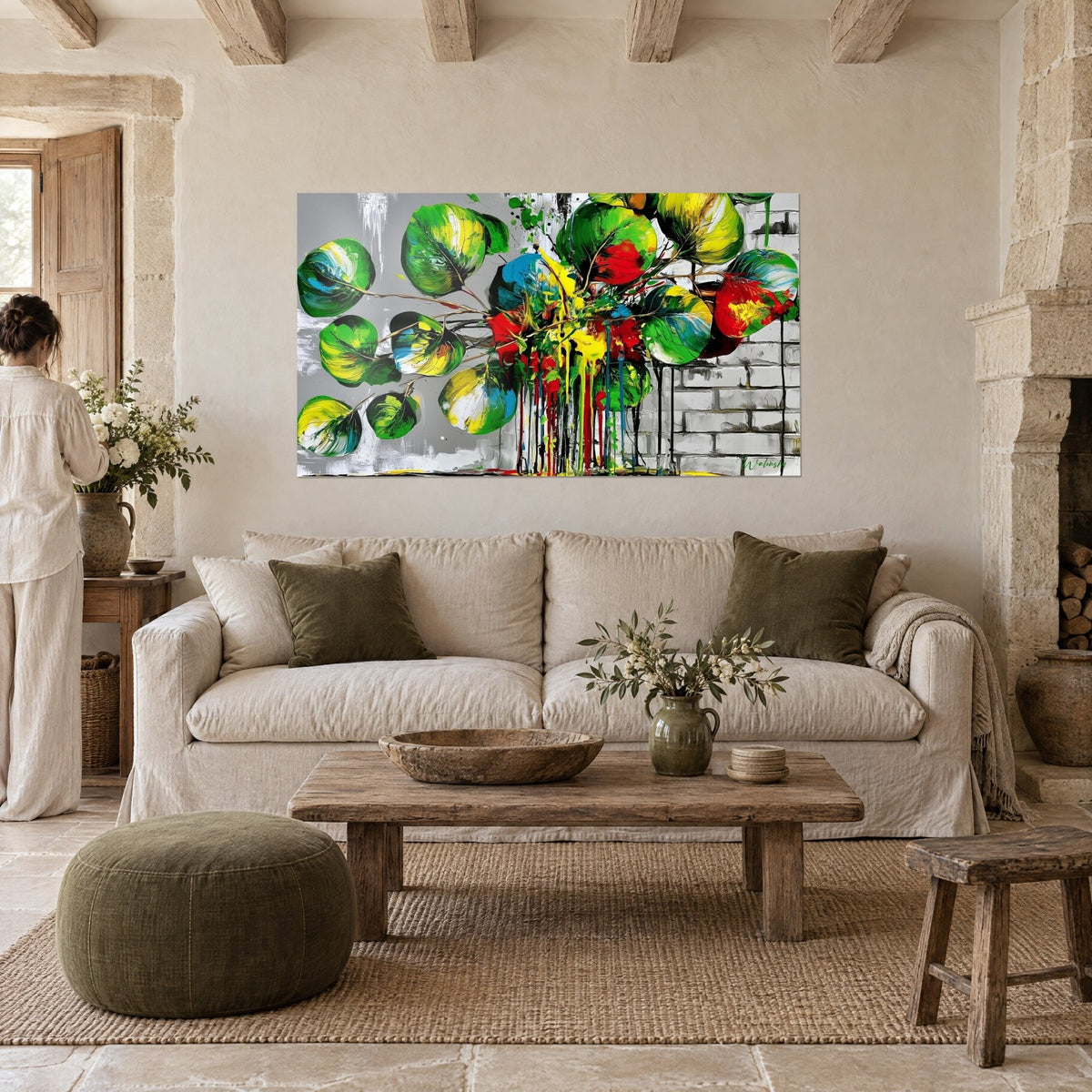 Tableau feuilles rondes vertes et rouges aux coulures vives, mur de briques gris, au-dessus d'un canapé dans un salon lumineux