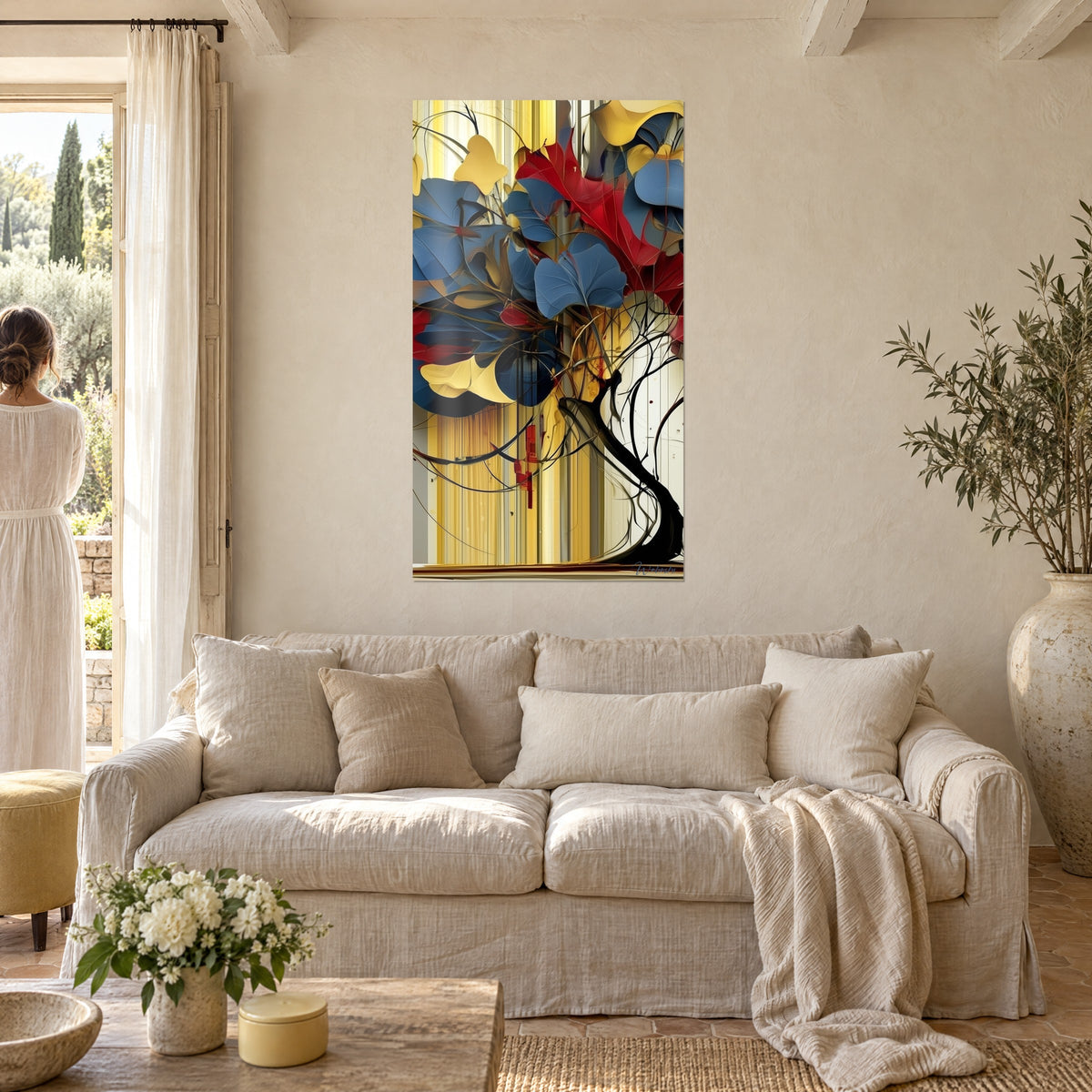 Tableau arbre aux larges feuilles bleu ardoise et rouge carmin sur fond de rayures dorées, au-dessus d'un canapé dans un salon lumineux