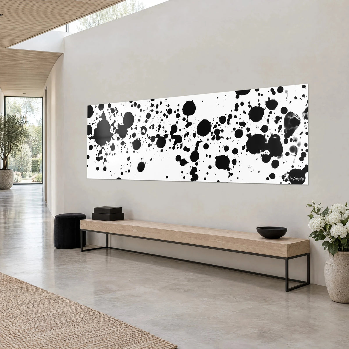 Quadro con gocce di inchiostro nero proiettate su fondo bianco, formato panoramico, appeso sopra una panca in legno chiaro