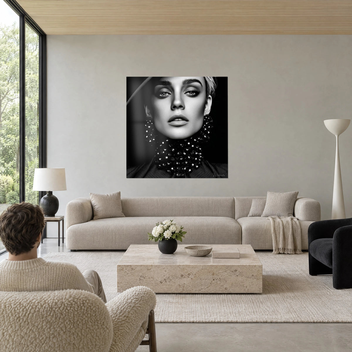 Cuadro rostro de modelo en blanco y negro, ojos perfilados con kohl, collar de perlas negras, encima de un sofá en un salón luminoso