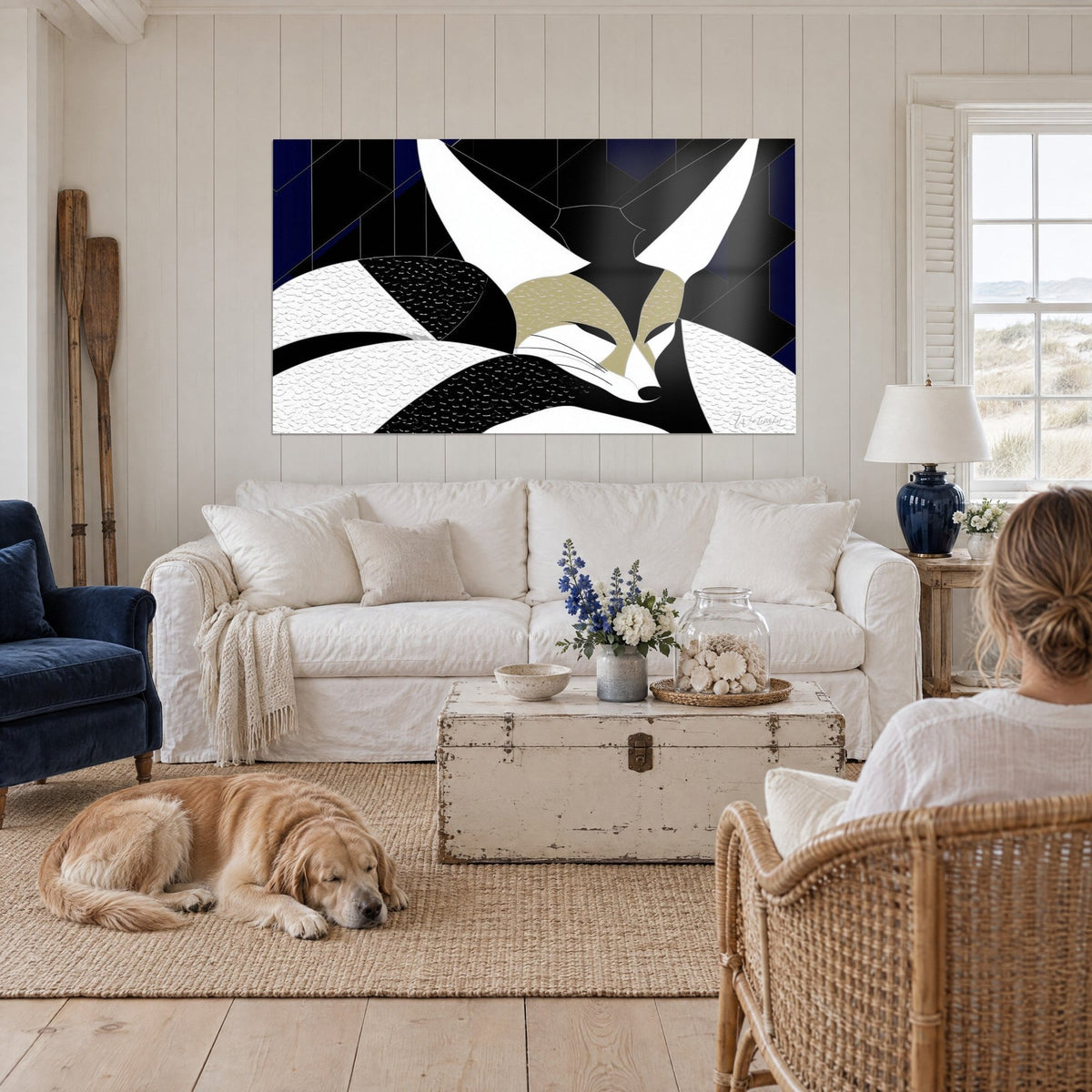 Cuadro zorro del desierto de orejas blancas, negro y beige, sobre fondo azul marino, encima de un sofá en un salón luminoso