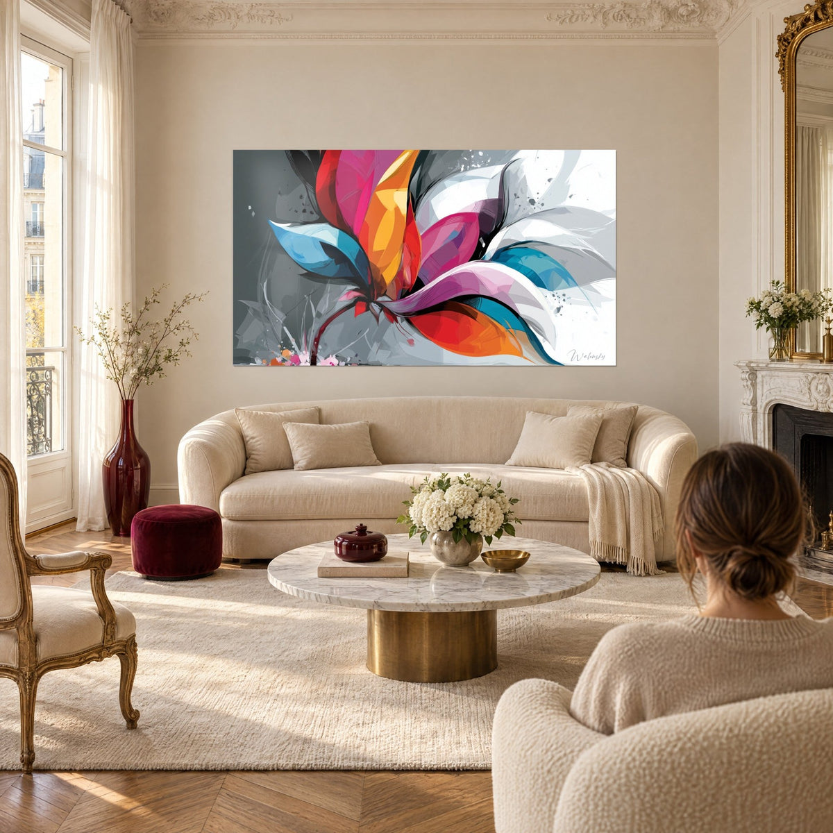 Wall art abstract flower with orange, magenta and turquoise blue petals on a grey background, above a sofa in a bright living room