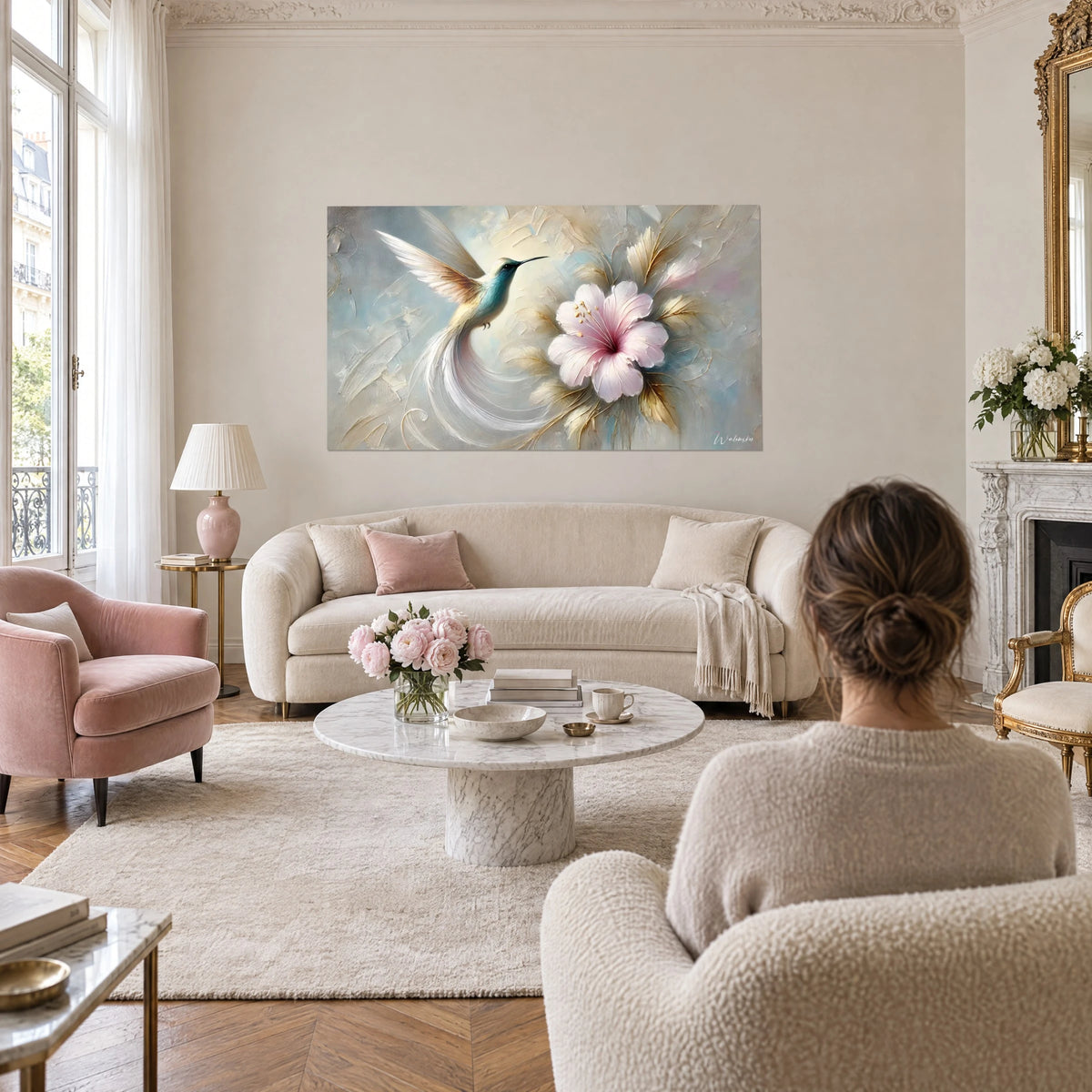 Gemälde mit türkisfarbenem Kolibri im Flug vor einem blassrosa Hibiskus, elfenbeinfarbene und goldene Federn, über einem Sofa in einem hellen Wohnzimmer