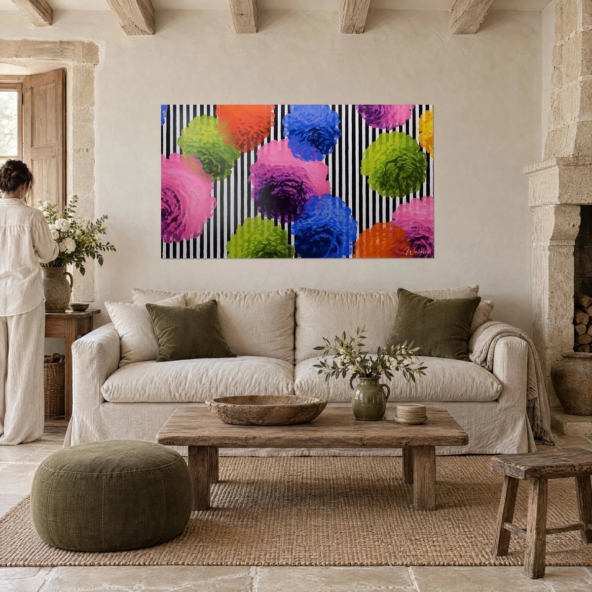 Wall art giant peonies in pink and anise green on black and white stripes, woman seen from behind, above a sofa in a bright living room