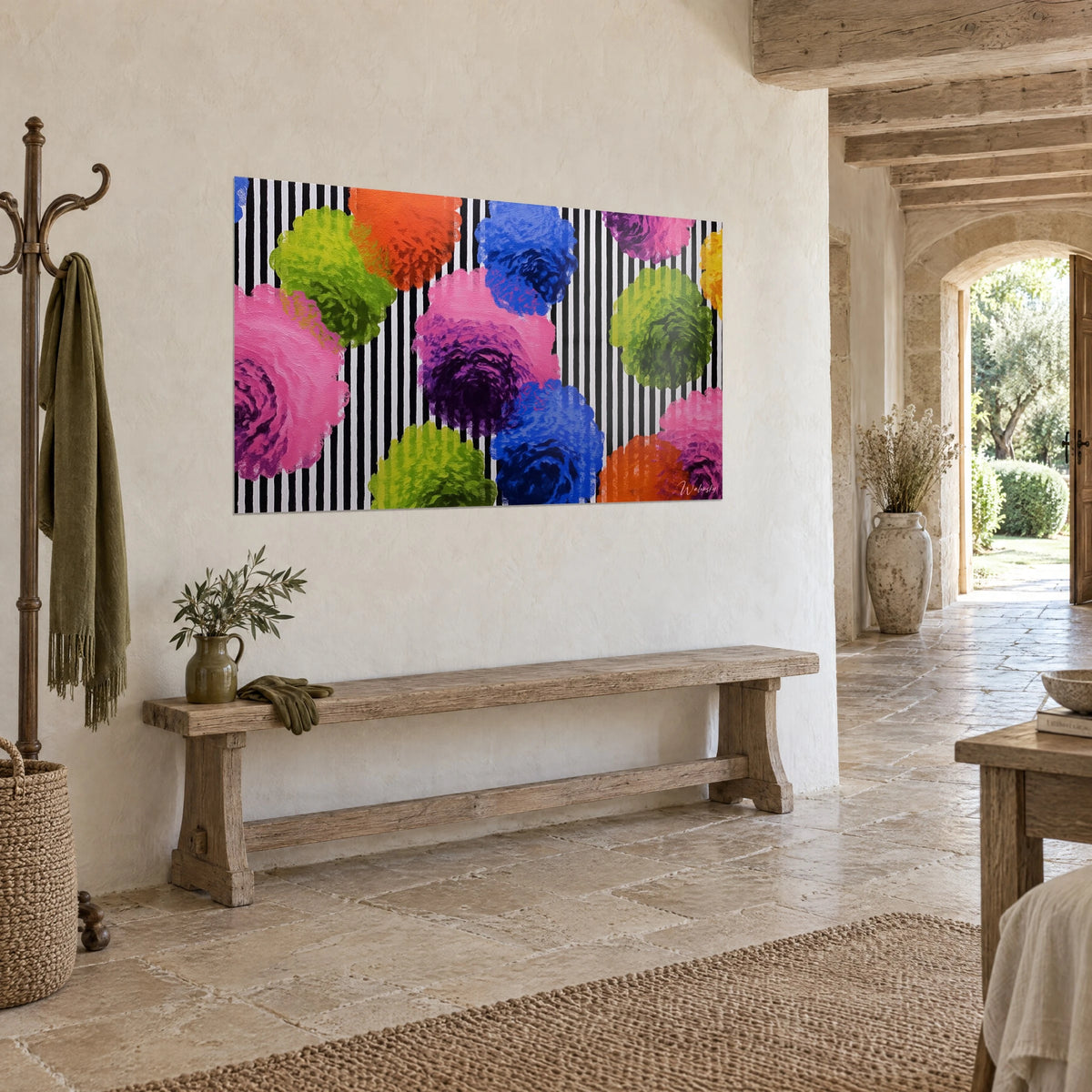 Wall art pom-pom bouquet in orange and cobalt blue on a black and white zebra-striped background, stone wall and wooden bench, three-quarter view
