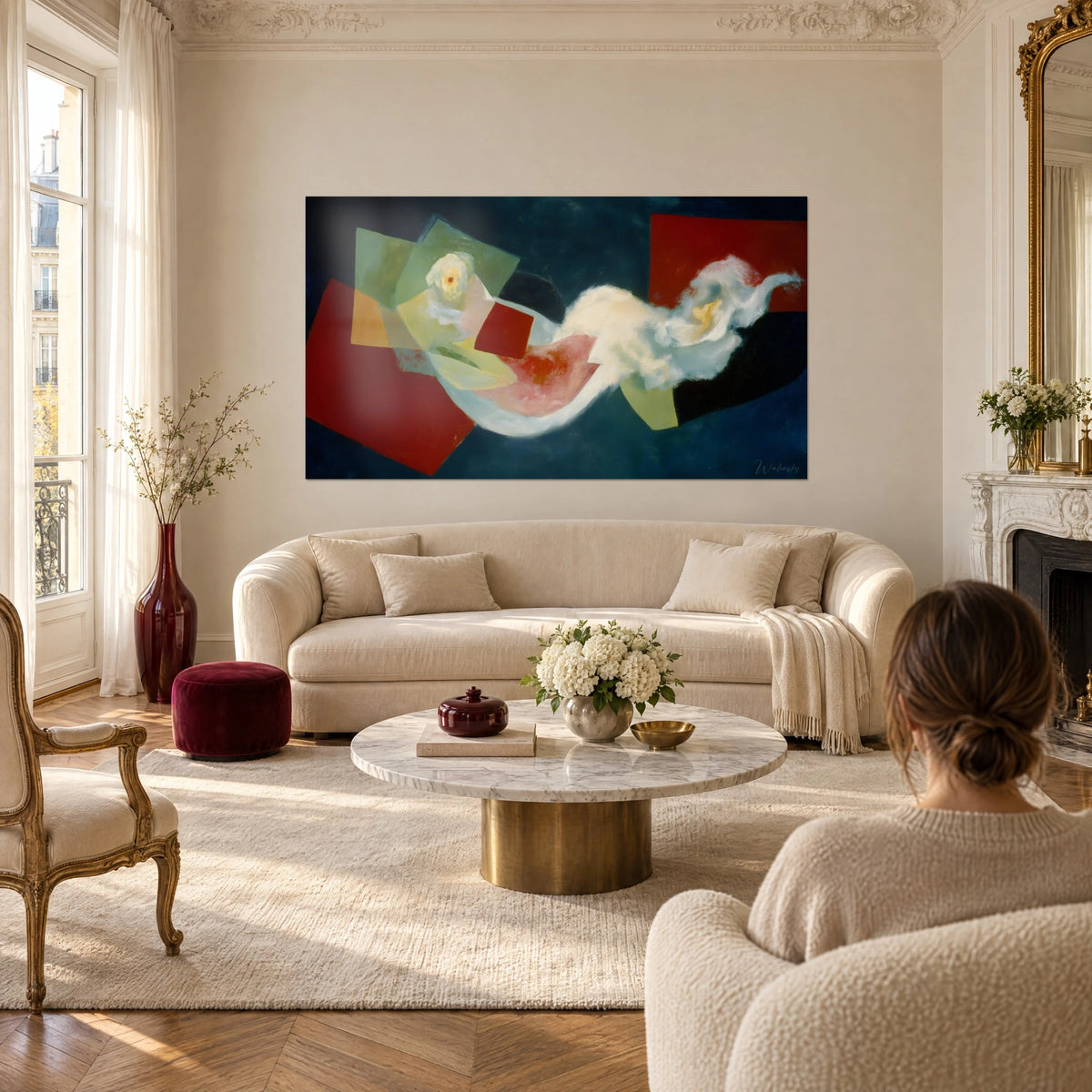 Tableau formes cubistes rouge carmin sur fond bleu nuit, voile blanc ondulant, femme de dos, au-dessus d'un canapé dans un salon lumineux
