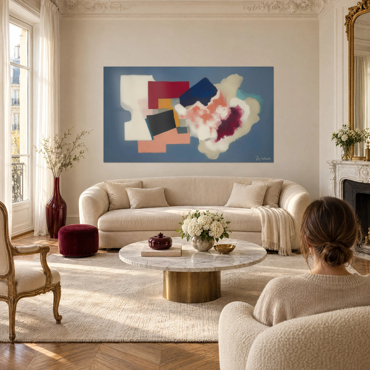 Quadro collage di forme geometriche in rosso carminio e blu navy su fondo blu ardesia, sopra un divano in un soggiorno luminoso