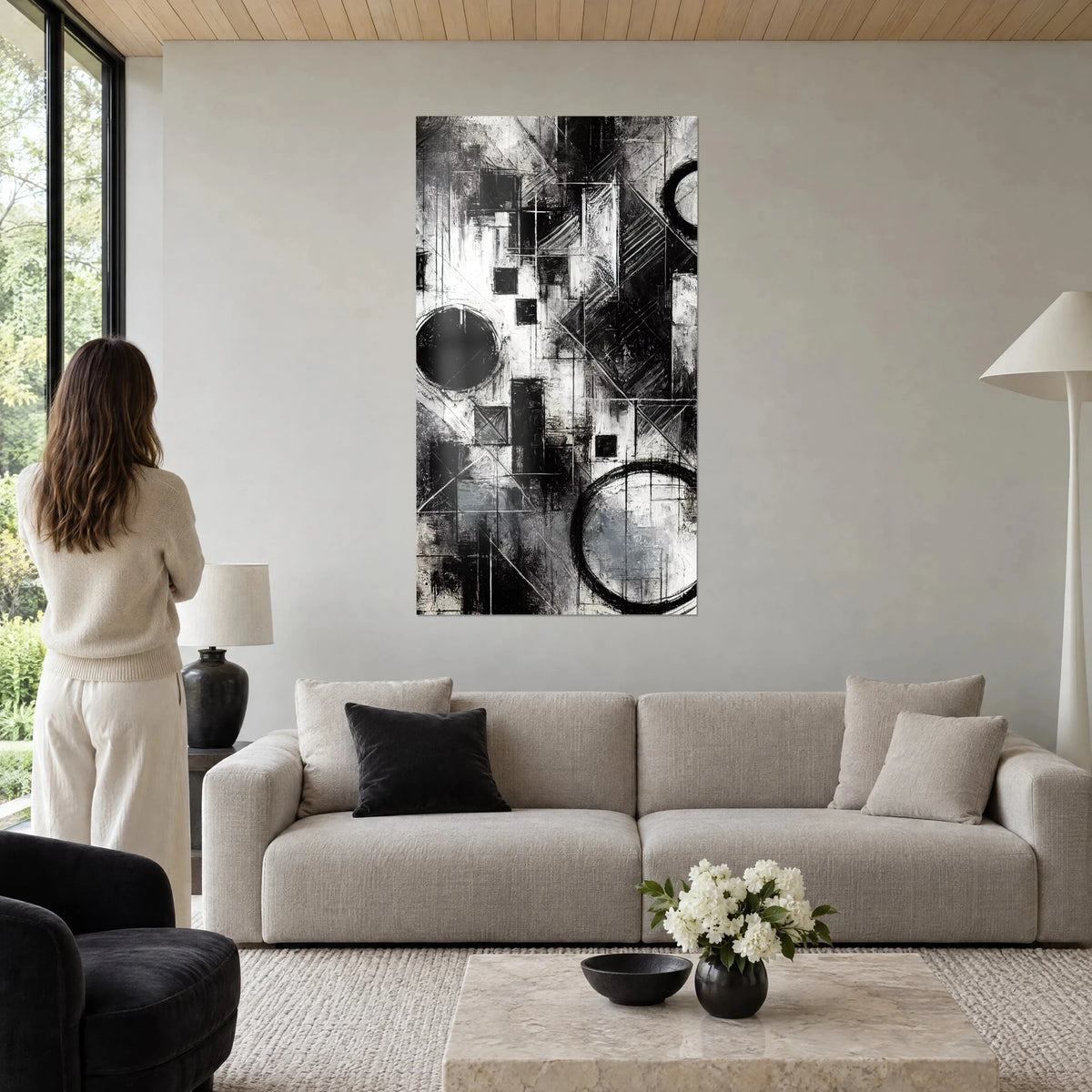 Tableau composition géométrique noir et blanc, cercles charbonneux et carrés sombres, au-dessus d'un canapé dans un salon lumineux