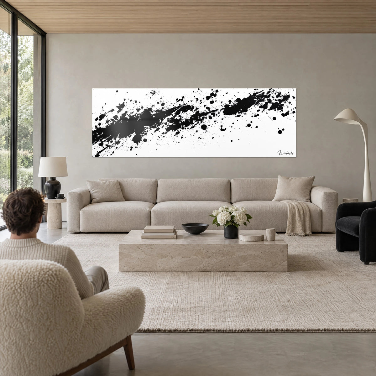 Gemälde mit schwarzen Tintenspritzern auf weißem Grund, tropfender Regen, Rückenansicht einer Person über einem Sofa in einem hellen Wohnzimmer