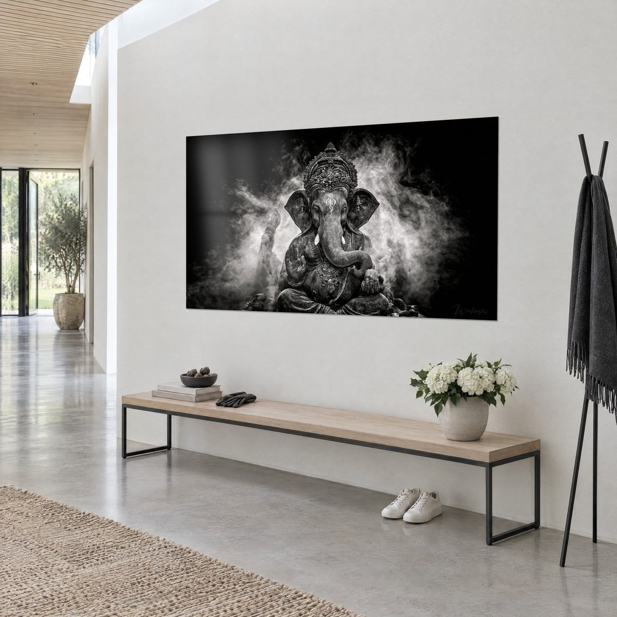 Wall art elephant deity seated on a lotus, cloud of silvery mist on deep black background, white wall, wooden console and entryway bench