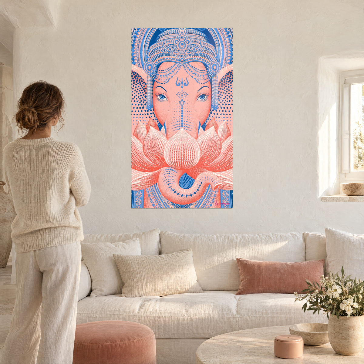 Tableau éléphant corail coiffé d'un diadème bleu, lotus pointillé, femme de dos au-dessus d'un canapé dans un salon lumineux