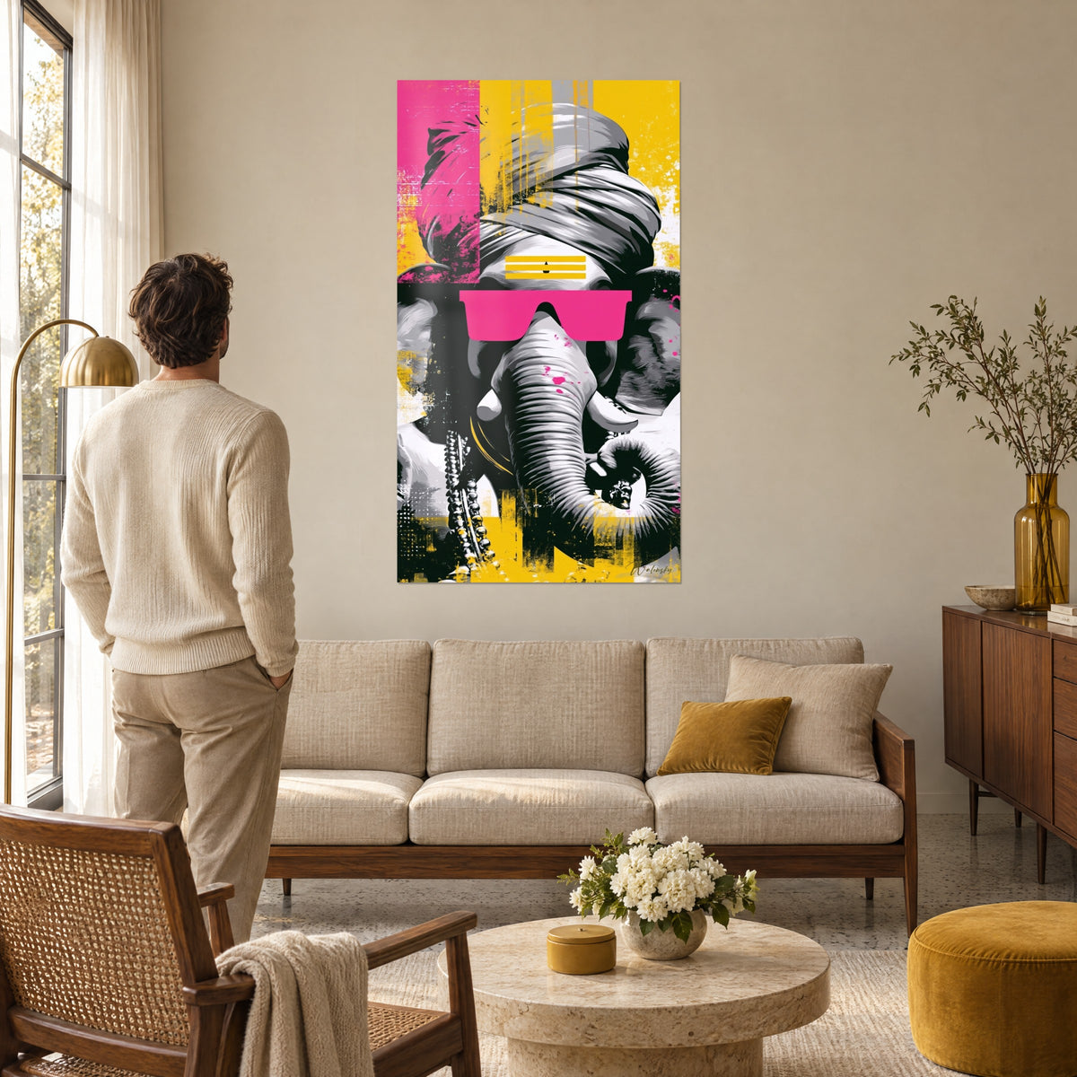Wall art Ganesh elephant wearing a draped grey turban and fluorescent pink glasses, mustard yellow background, above a sofa in a bright living room
