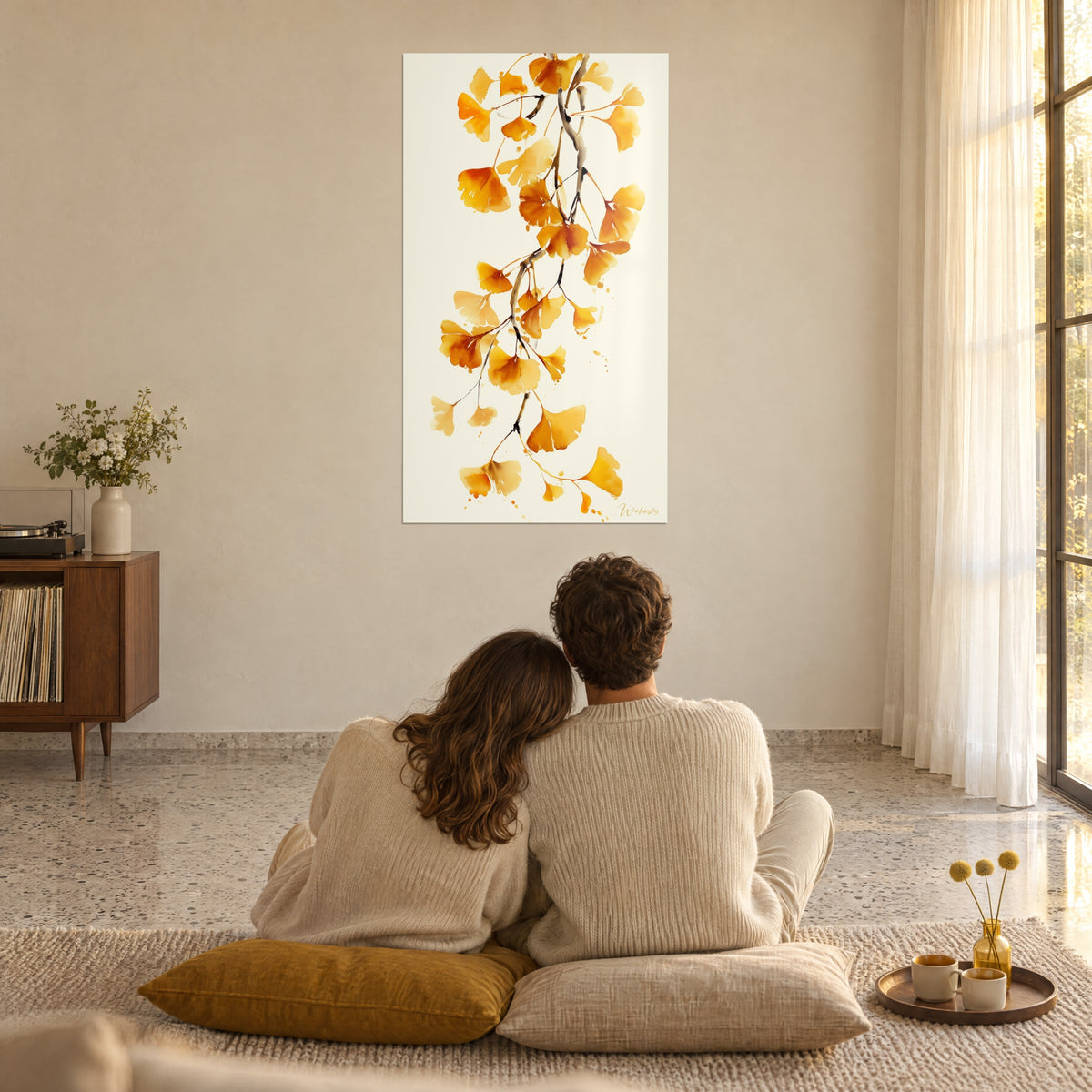 Schilderij gouden ginkgo die in een arabesk valt op ivoorkleurige achtergrond, koppel met de rug naar de kijker op mosterdgele kussens, zonovergoten woonkamer
