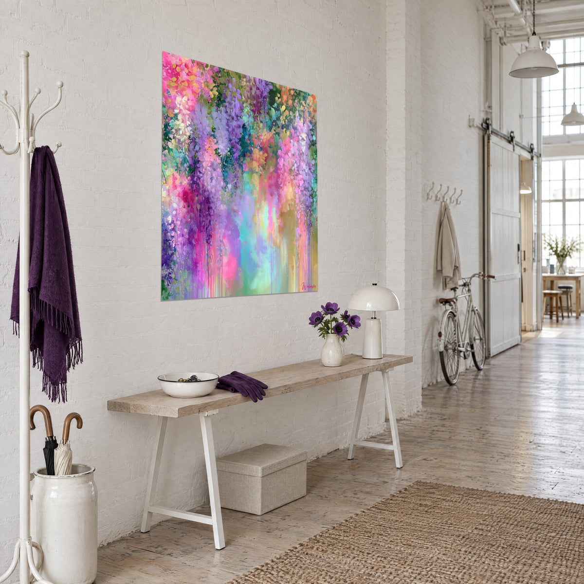 Wall art with a cascade of purple and pink flowers, emerald green foliage, three-quarter view of a wooden entryway bench