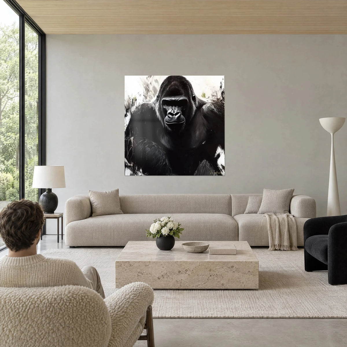 Quadro di gorilla dallo sguardo serio, pelo nero e contorni bianchi, spettatore di spalle, sopra un divano in un soggiorno luminoso