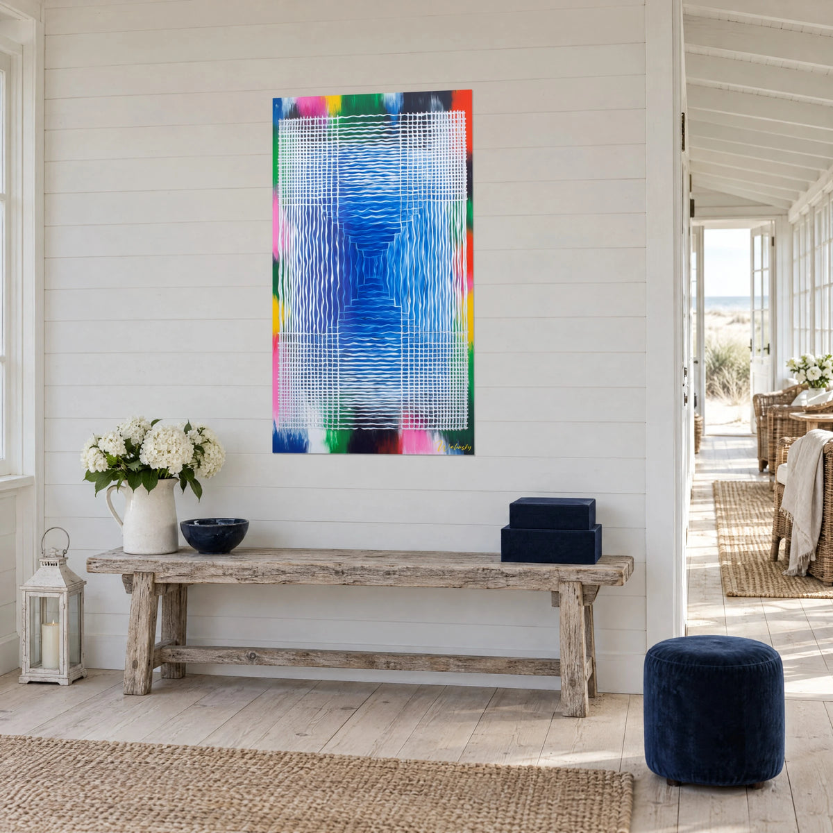 Wall art with a royal blue optical tunnel surrounded by a silver grid and orange and yellow stripes, three-quarter view, in a seaside house