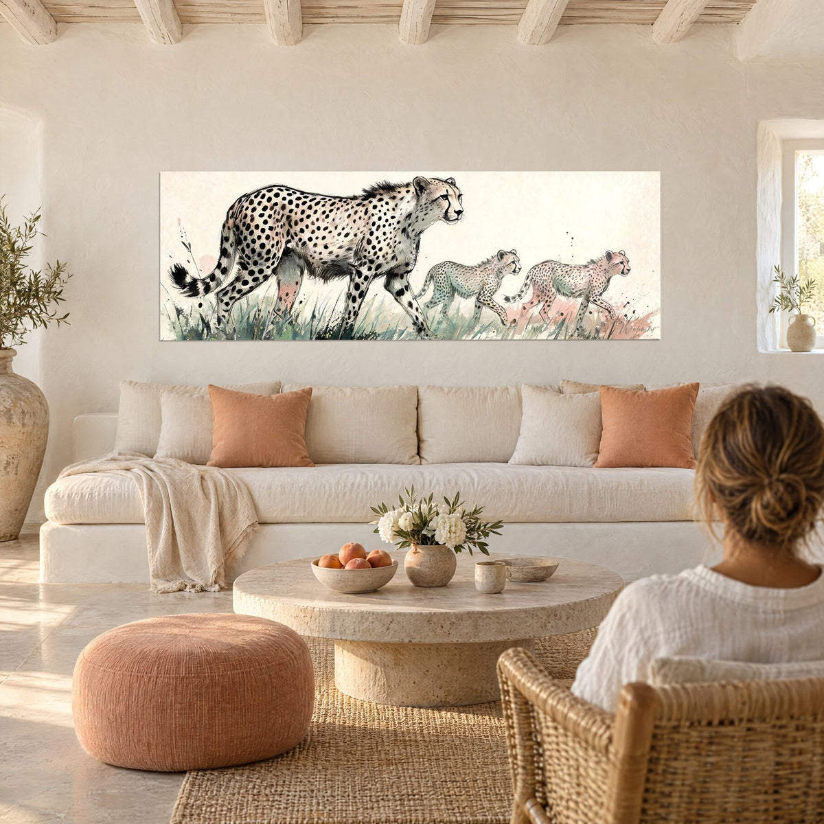 Quadro ghepardo maculato e i suoi due cuccioli in acquerello avorio e rosa, sopra un divano in un soggiorno luminoso