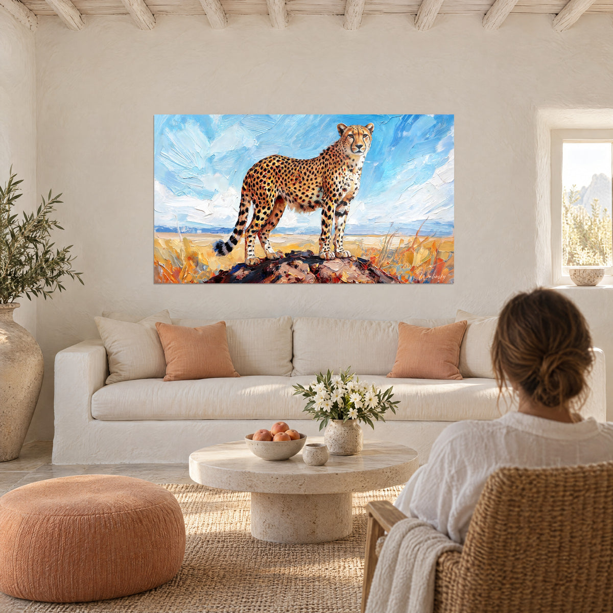 Tableau guépard tacheté dressé sur son rocher, ciel bleu et nuages blancs épais, herbes ocre, au-dessus d'un canapé dans un salon lumineux