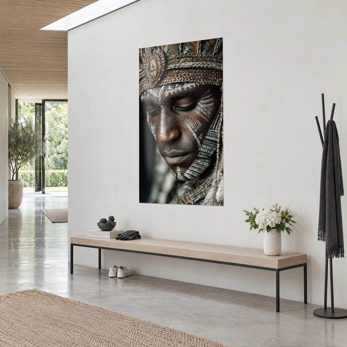 Wall art of a close-up tribal portrait, ivory chalk motifs on coppery skin, beige feathers, on a white wall beside a wooden bench