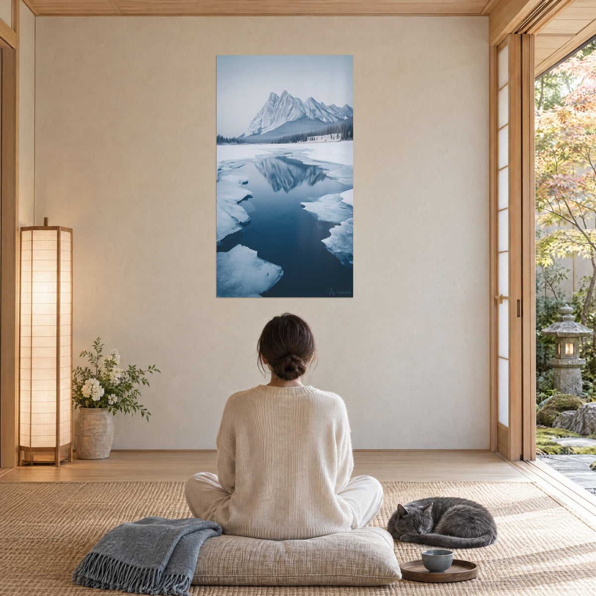 Tableau glacier et cime neigeuse réfléchie en bleu et blanc, femme de dos en méditation, chat gris sur un coussin, pièce japandi