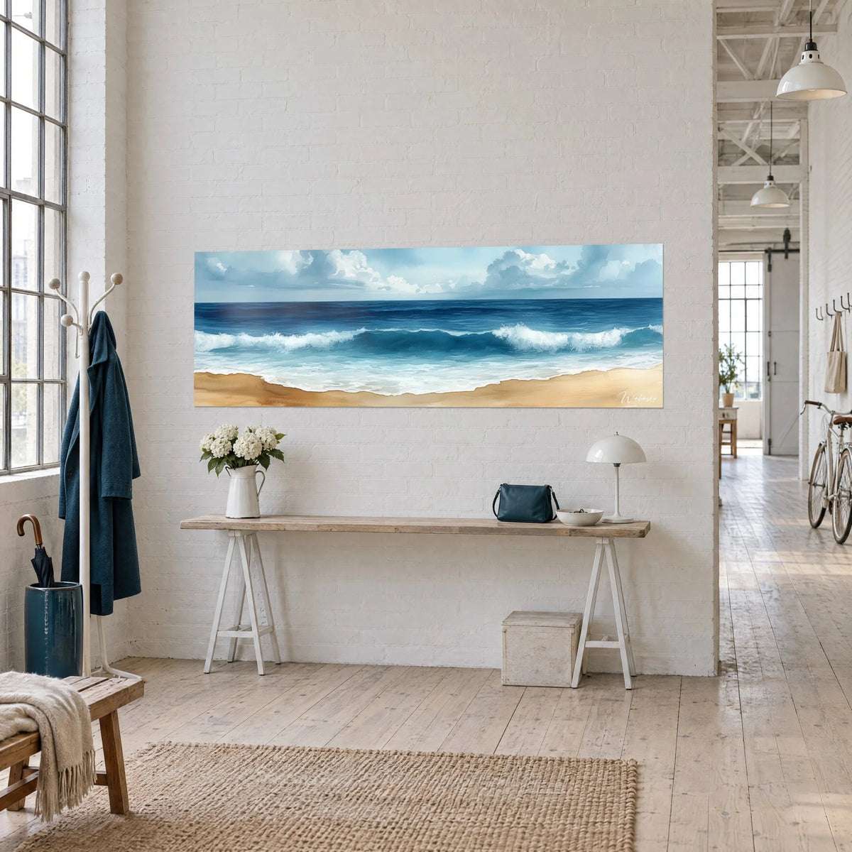 Wall art panoramic view of an indigo ocean with white-capped waves, a band of golden sand and grey-blue clouds, hung on a loft wall