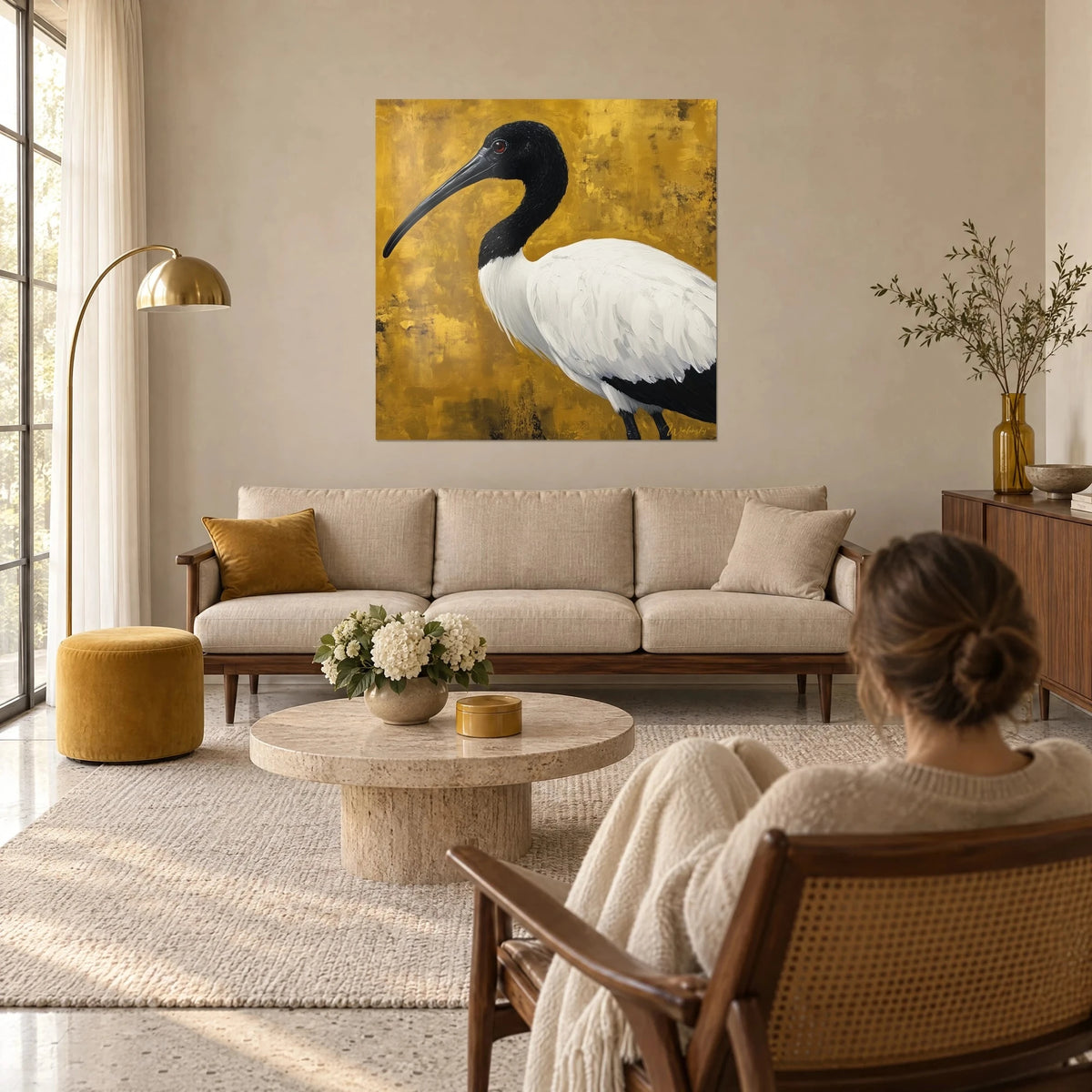 Wall art sacred ibis with long black beak on patinated gold background, thick white plumage, above a sofa in a bright living room