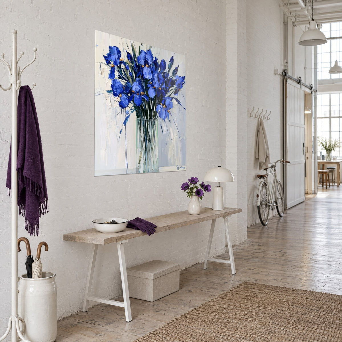 Cuadro flores de iris pintadas con espátula, azul ultramar y blanco crema, colgado en una pared de loft junto a una consola de madera