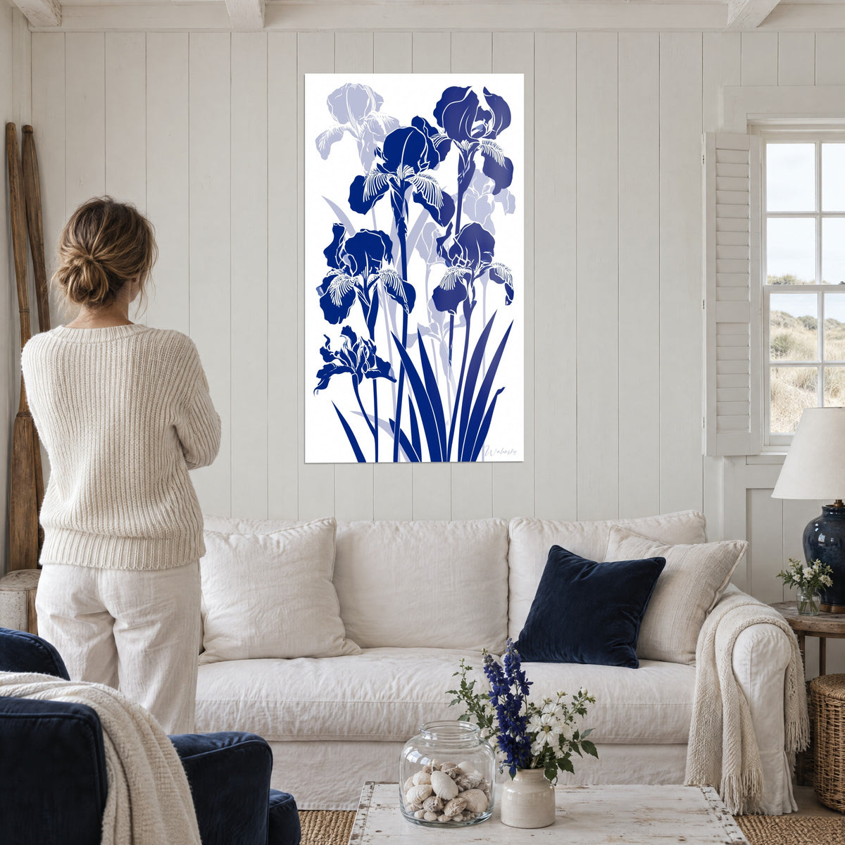 Cuadro iris en silueta azul marino sobre fondo blanco, pétalos con flecos, encima de un sofá en un salón luminoso