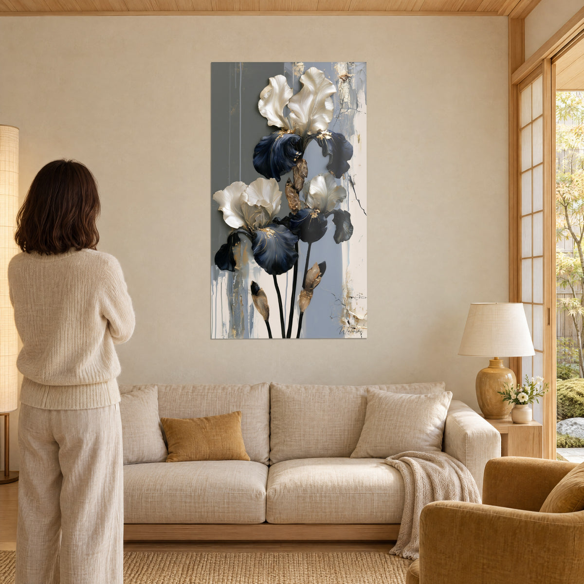 Cuadro iris nacarados con pétalos marfil y azul marino, fondo gris rayado, mujer de espaldas, sobre un sofá en un salón luminoso