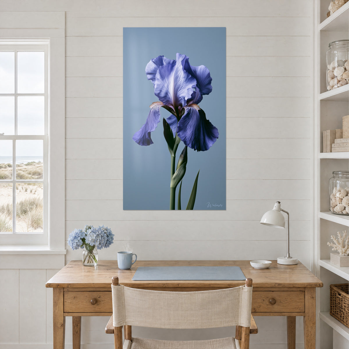 Schilderij iris in vinca-blauw en donkergroene steel op grijsblauwe achtergrond, witte muur naast een bureau van licht hout