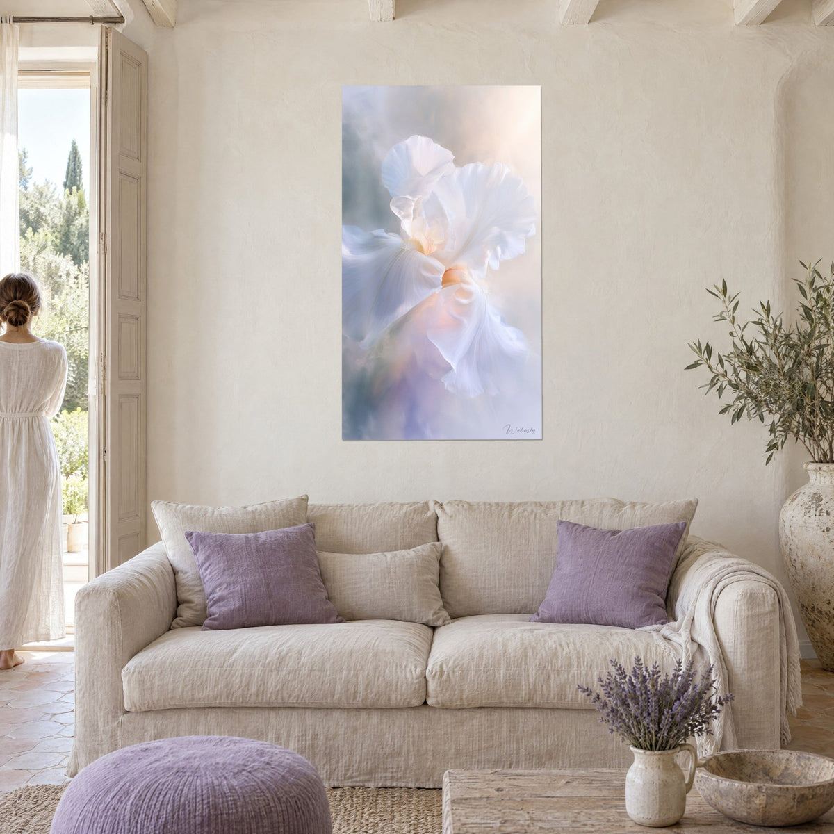 Quadro iris bianco dai petali stropicciati, riflessi dorati e lavanda, con una donna di spalle sopra un divano in un soggiorno luminoso