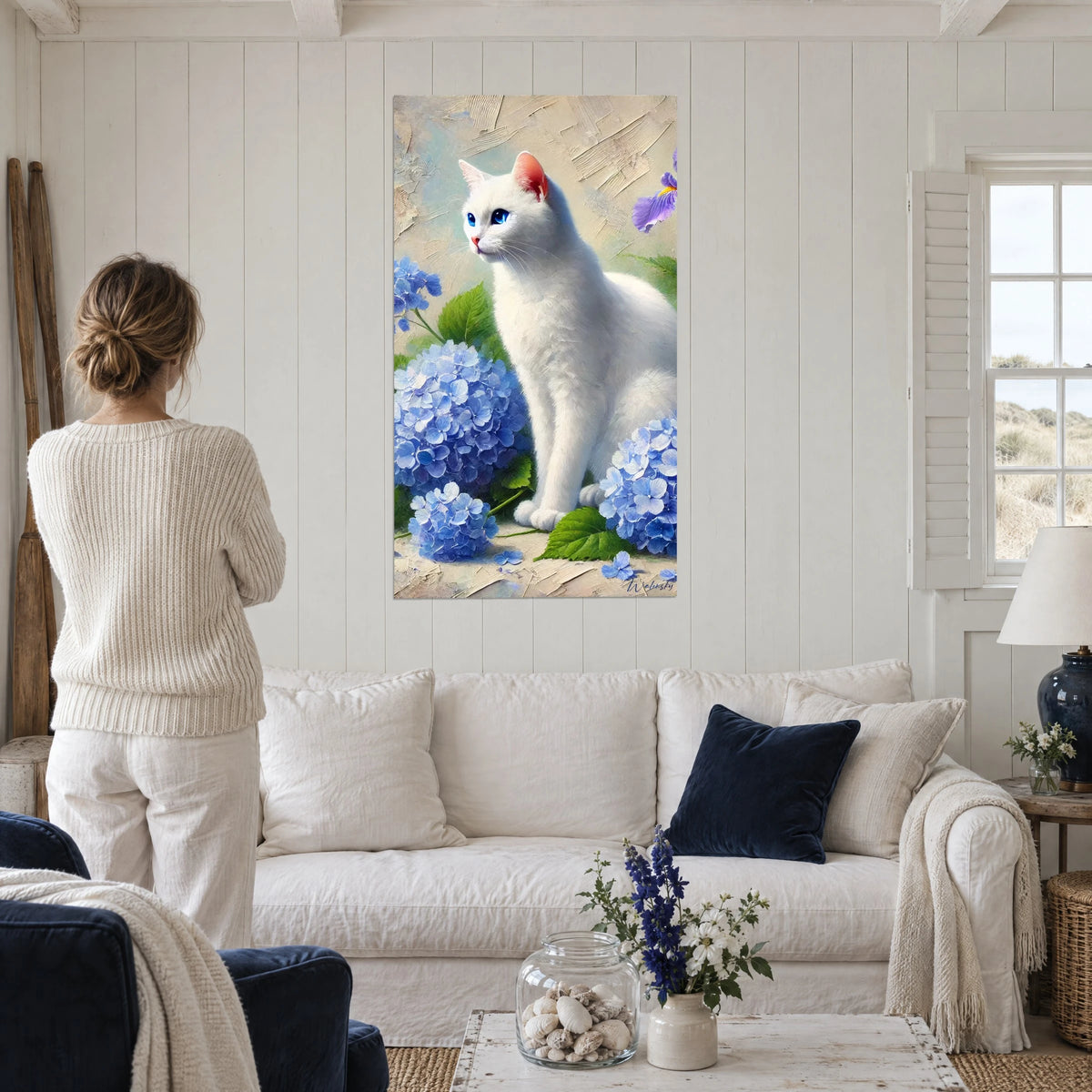 Cuadro gato blanco de ojos azules sentado entre hortensias azules, verde suave, encima de un sofá en un salón luminoso