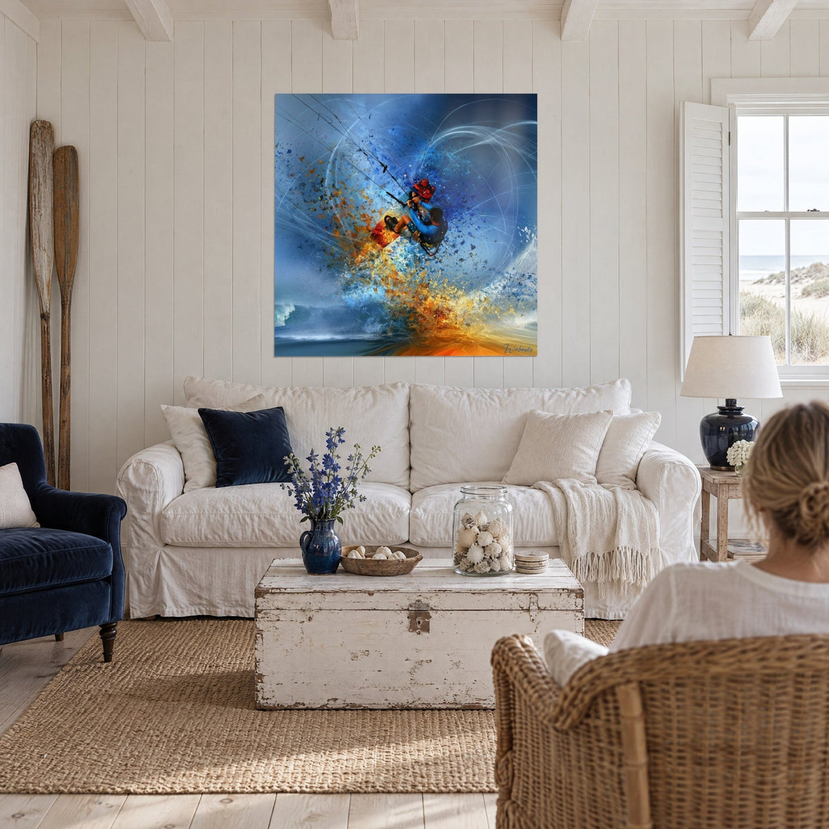 Wall art kitesurfer in a blue wetsuit leaping through a burst of orange and azure sparks, above a sofa in a bright living room