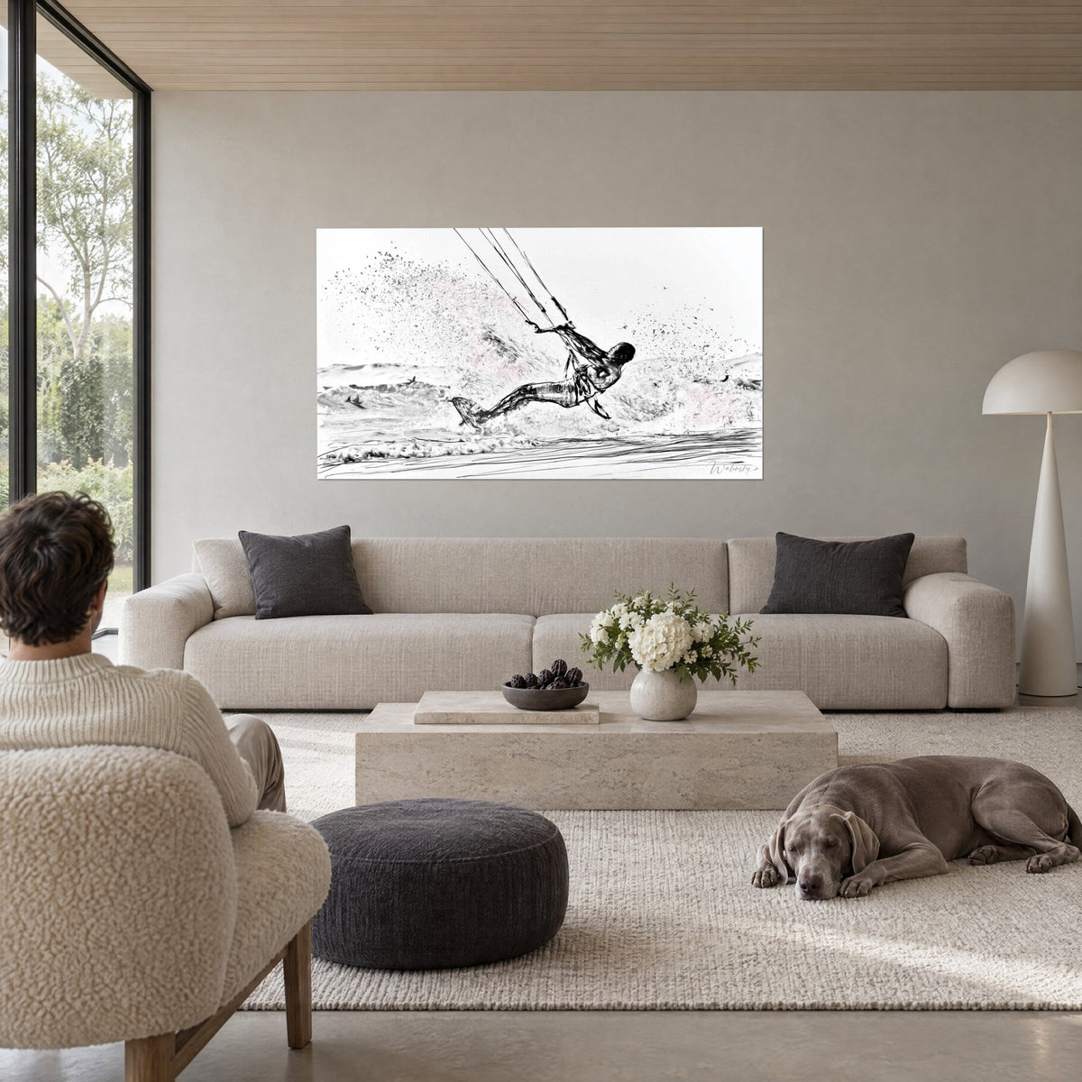 Cuadro kitesurfista suspendido en el aire, salpicaduras de espuma en blanco y negro, dibujo a lápiz, sobre un sofá en un salón luminoso