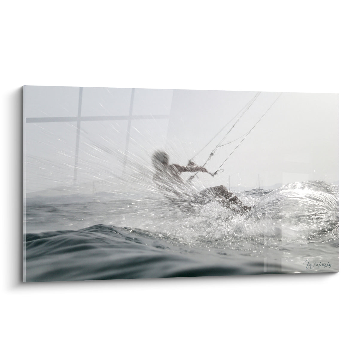 Kitesurfeur gris fendant une vague blanche, silhouette floue tirée par les lignes tendues