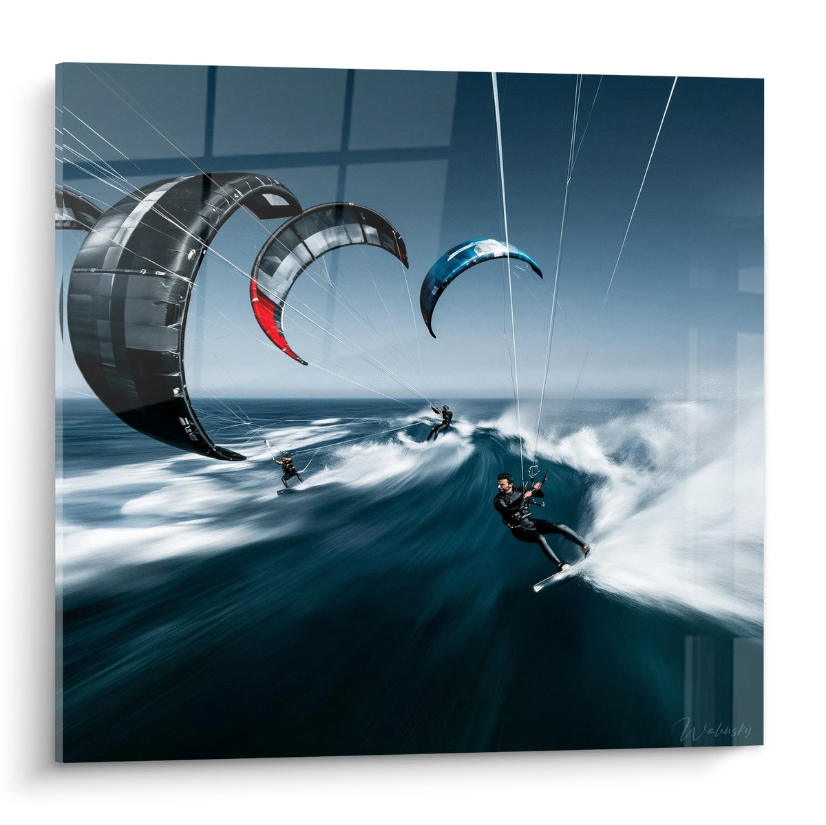 Trois kitesurfeurs en action sur une vague, voiles noires, rouge et bleu marine tendues au vent