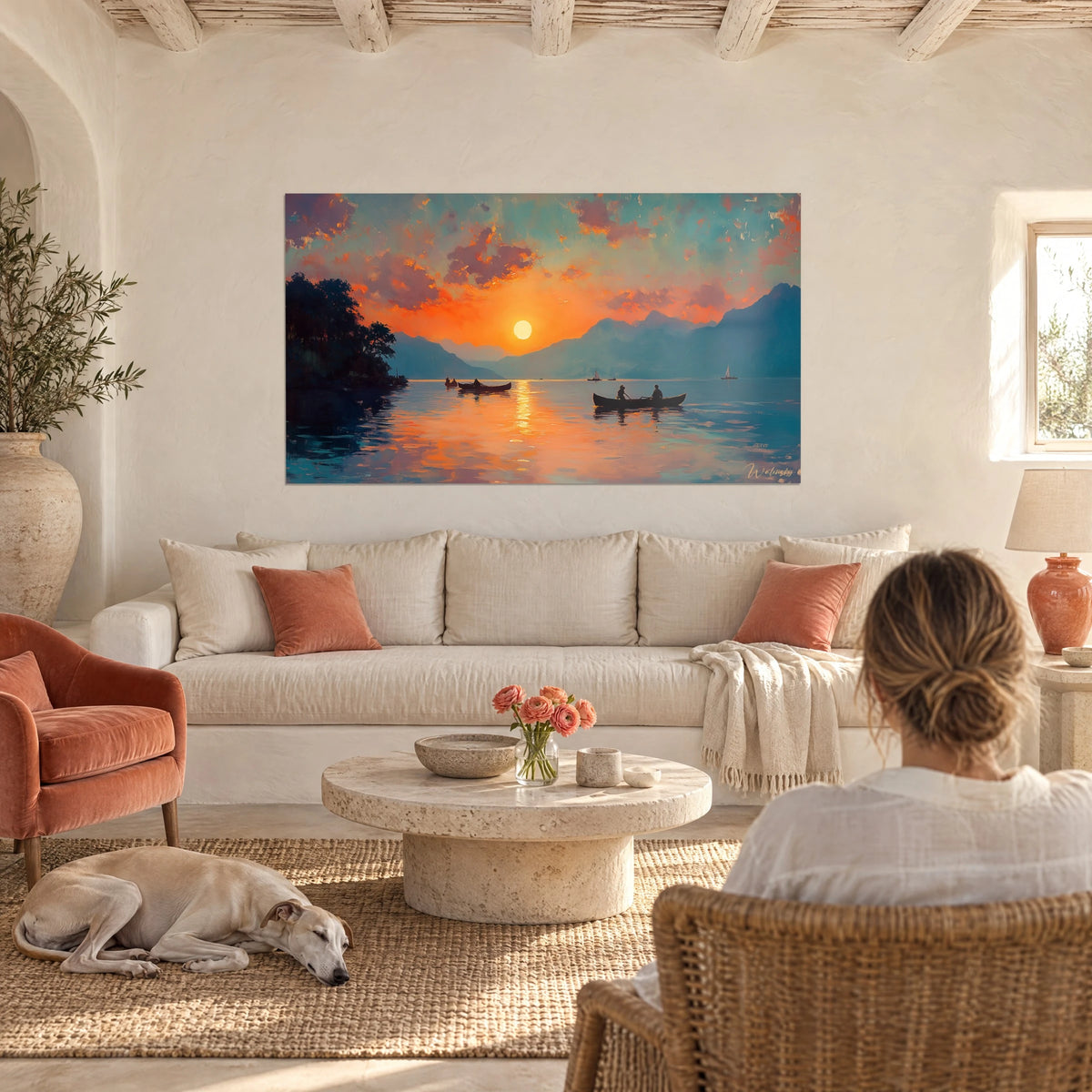 Quadro tramonto su un lago di montagna, cielo arancione e nuvole rosa, due barche nere, sopra un divano in un soggiorno luminoso