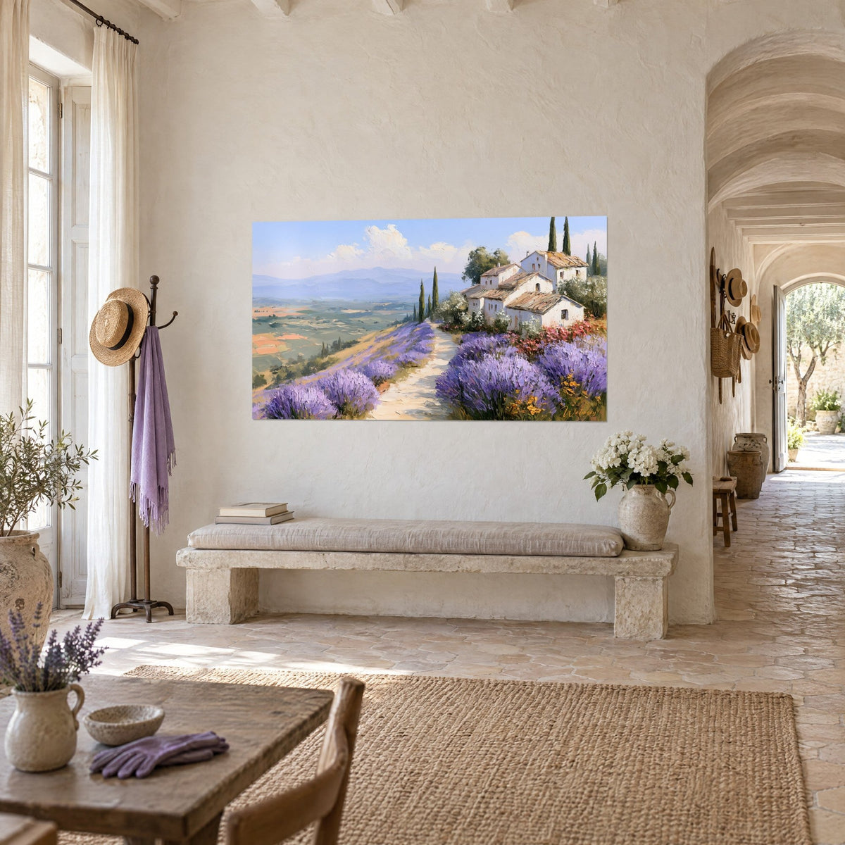 Wall art farmhouse with white walls and dark cypress trees against a blue-green valley backdrop, hung in a vaulted corridor of the farmhouse's light stone