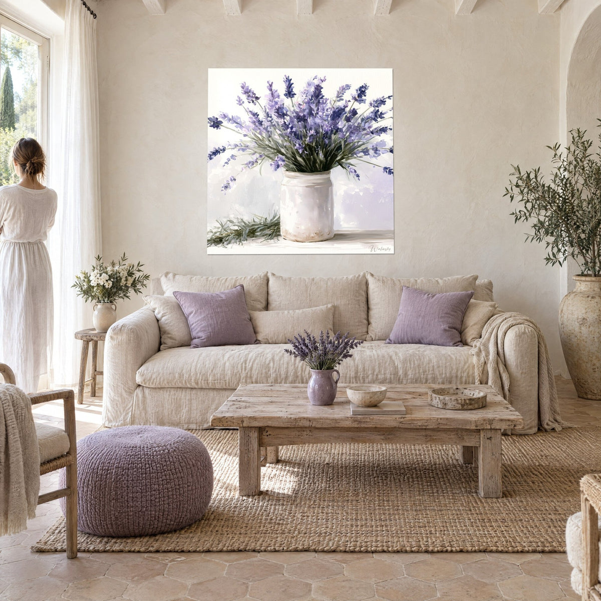 Cuadro ramo de lavanda malva en una maceta blanca, fondo crema; una mujer de espaldas, sobre un sofá en un salón luminoso
