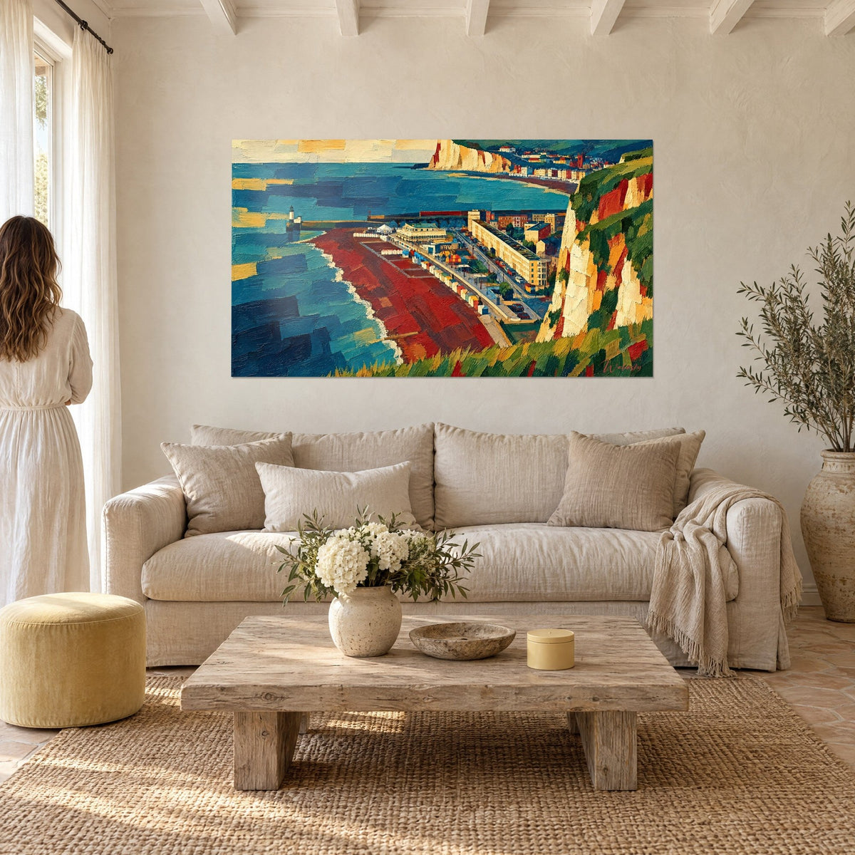 Gemälde Kreidefelsen in Ockertönen über einem rotbraunen Strand und türkisfarbenem Meer, Paar von hinten, über einem Sofa in einem hellen Wohnzimmer