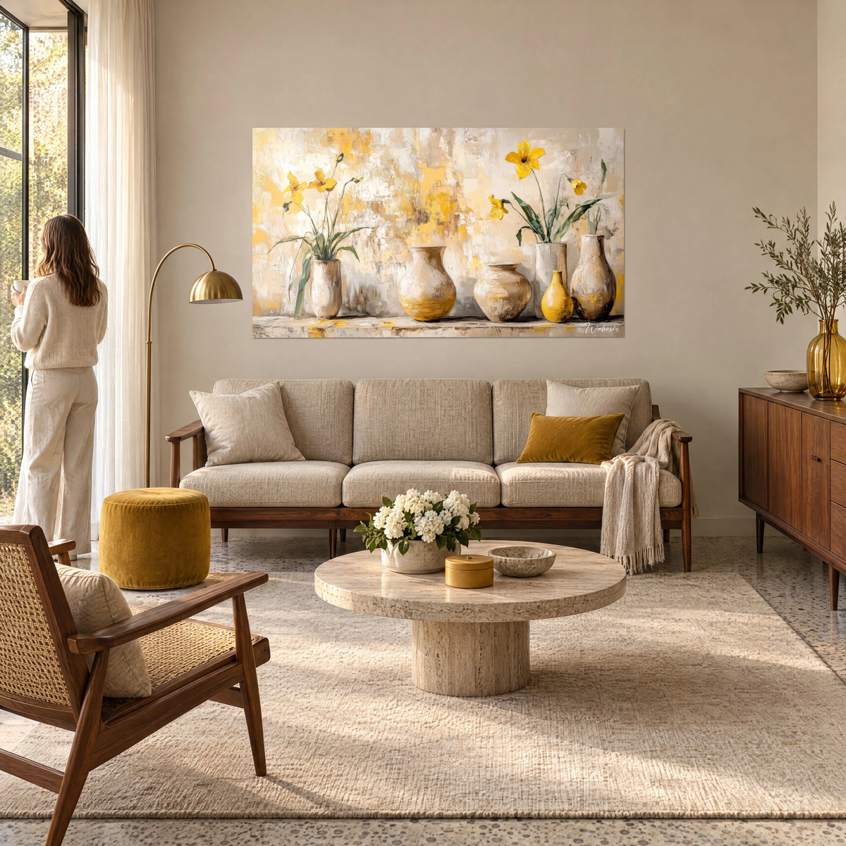 Cuadro Narcisos amarillo azafrán en jarrones de arcilla beige, pared patinada, mujer de espaldas, encima de un sofá en un salón luminoso