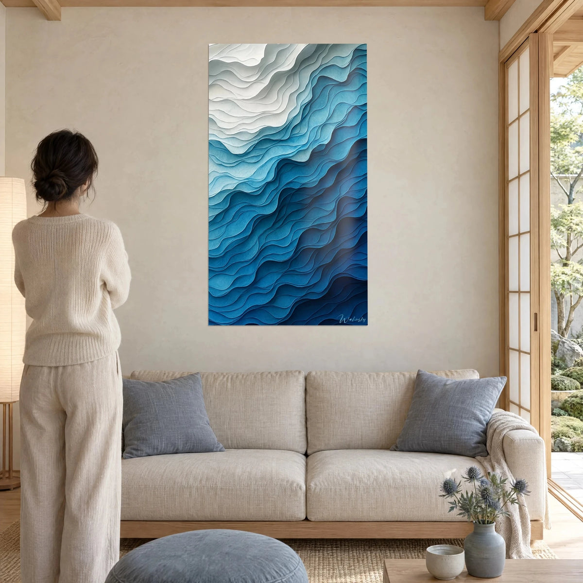 Tableau vagues de papier superposées, blanc nacré et bleu cyan, femme de dos, au-dessus d'un canapé dans un salon lumineux