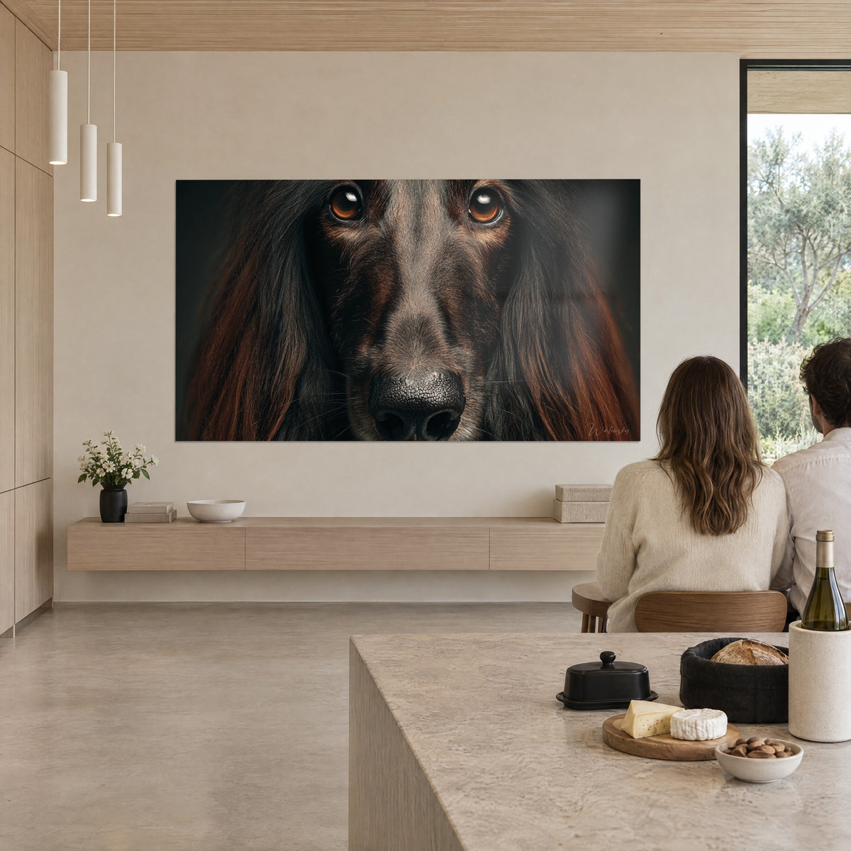 Cuadro galgo afgano en primer plano, mirada naranja quemado y orejas castaño oscuro, una pareja de espaldas junto a una isla de cocina de piedra