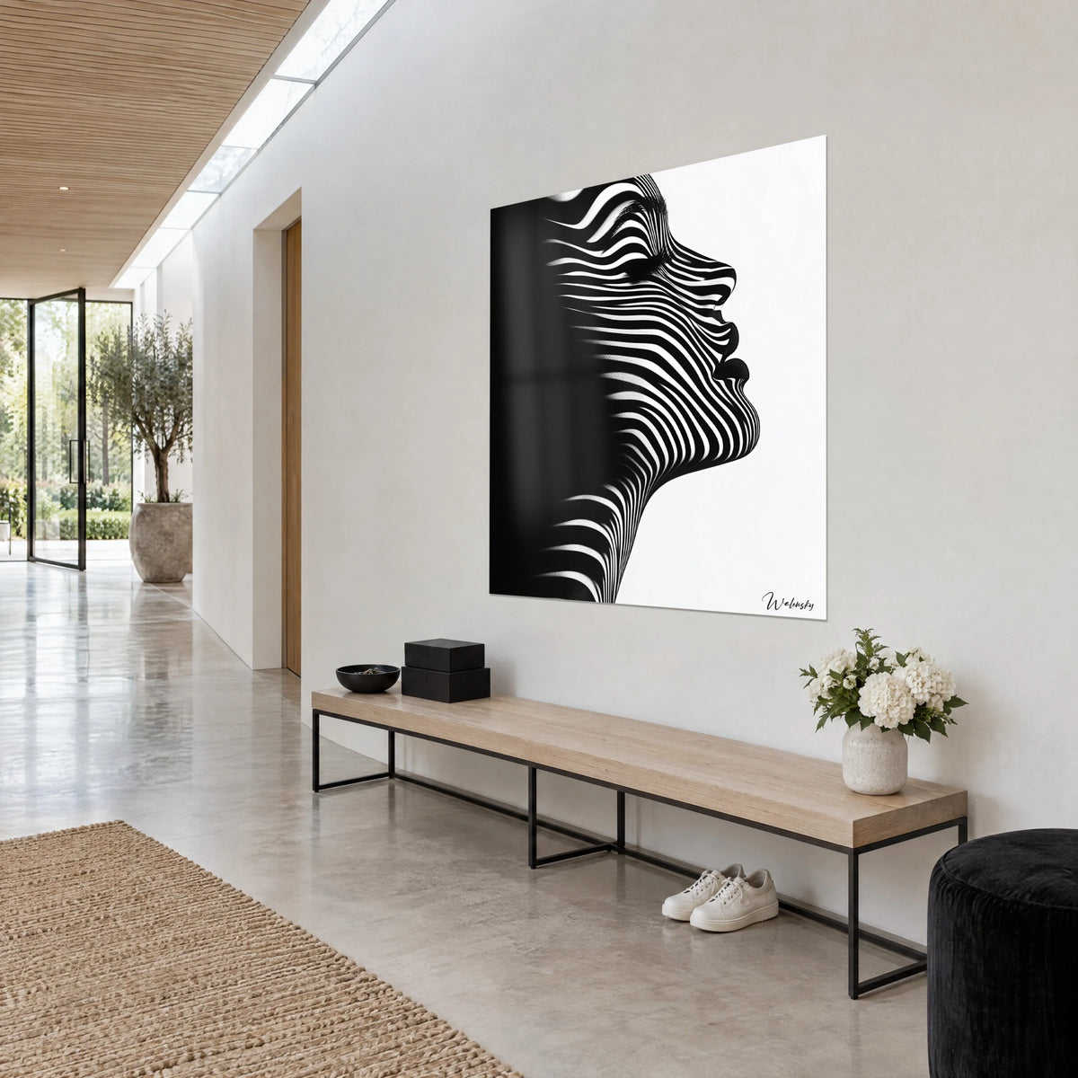 Quadro volto di donna in linee ondulate avorio ed ebano, naso e labbra in rilievo, appeso di tre quarti su una parete grigio chiaro