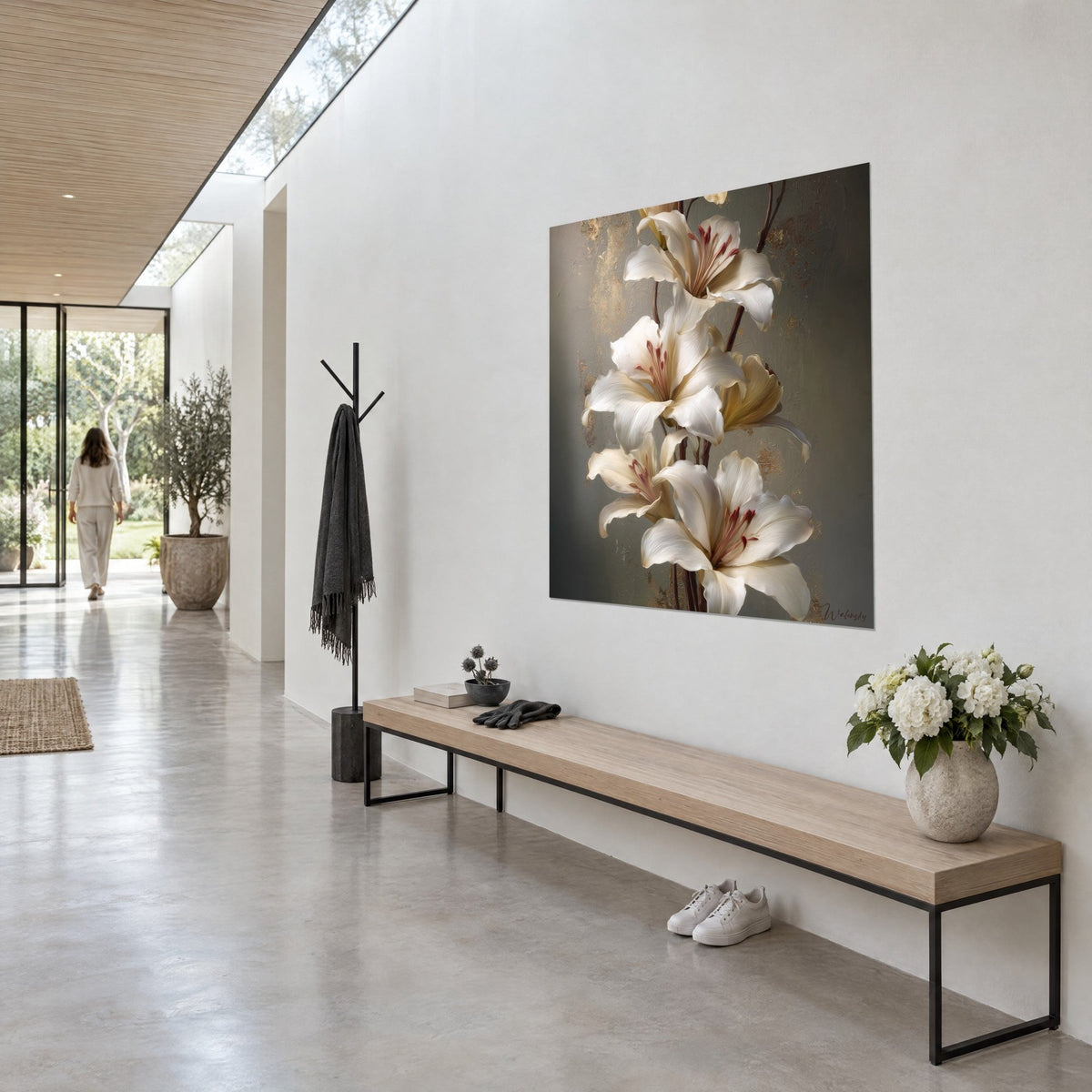 Tableau fleurs de lys ivoire aux pétales ondulés, fond taupe et touches dorées, accroché dans un couloir clair près d'un banc en bois