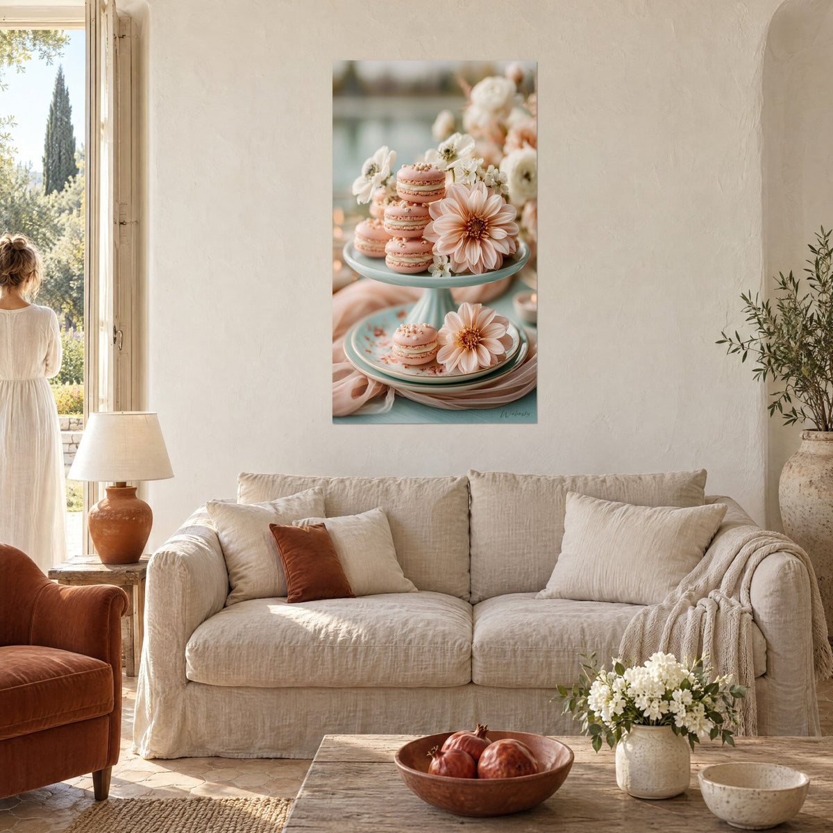 Tableau macarons roses empilés sur présentoir vert d'eau, fleurs ivoire et dahlia pêche, au-dessus d'un canapé dans un salon lumineux