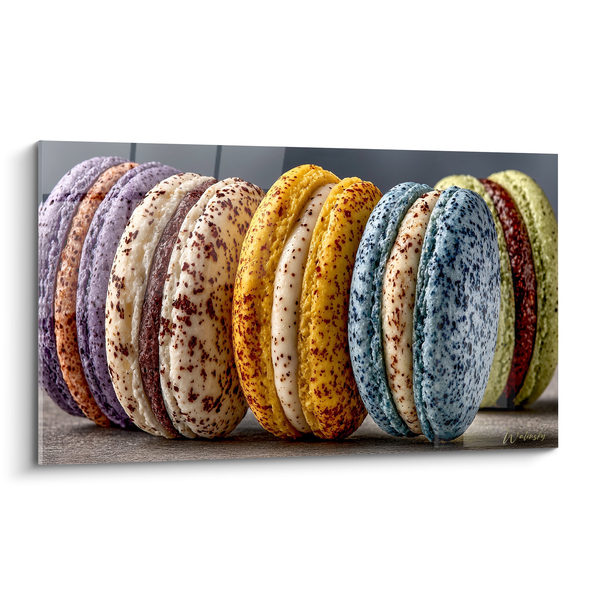 Macarons alignés violet lavande, jaune safran et bleu moucheté sur fond gris flou