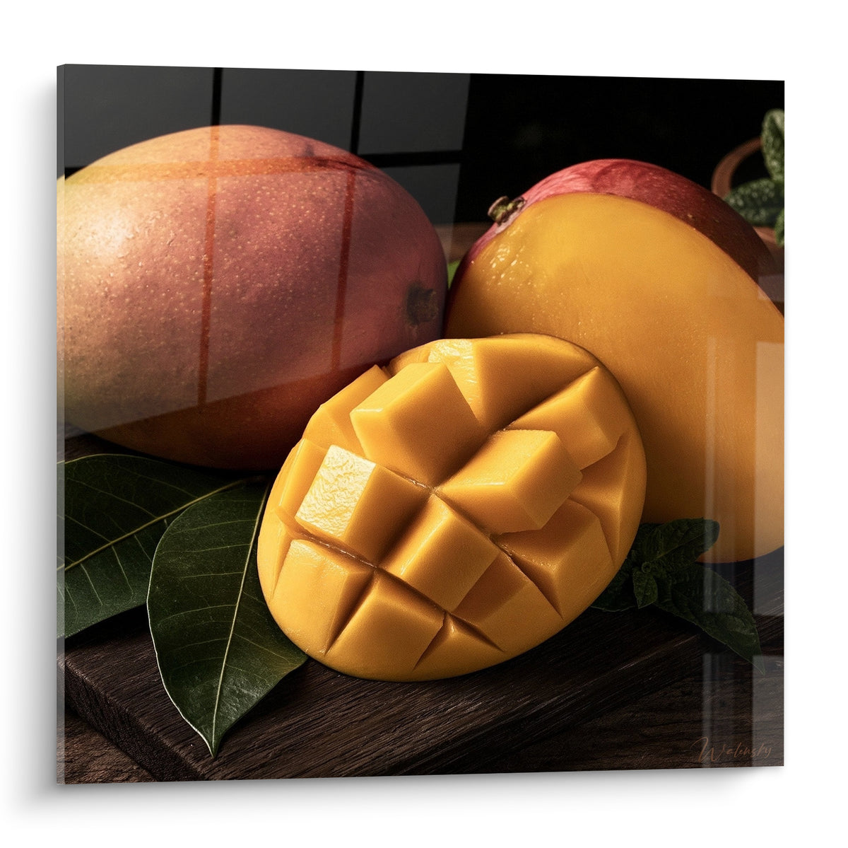 Mangue coupée en cubes dorés posée devant deux fruits entiers rouge et orangé sur bois sombre
