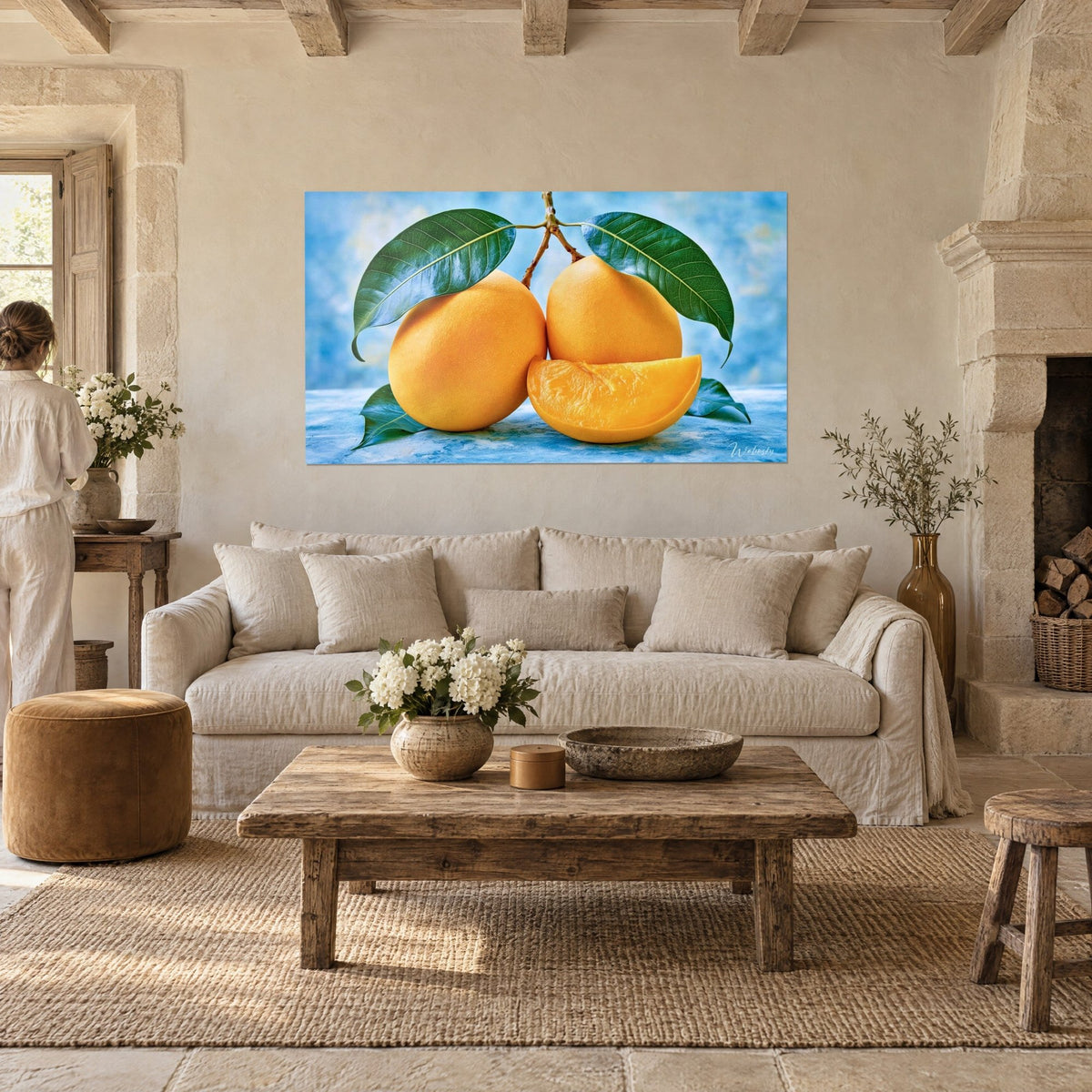 Tableau deux mangues jumelles orange vif, feuilles vert sombre sur fond bleu, personne de dos au-dessus d'un canapé dans un salon lumineux